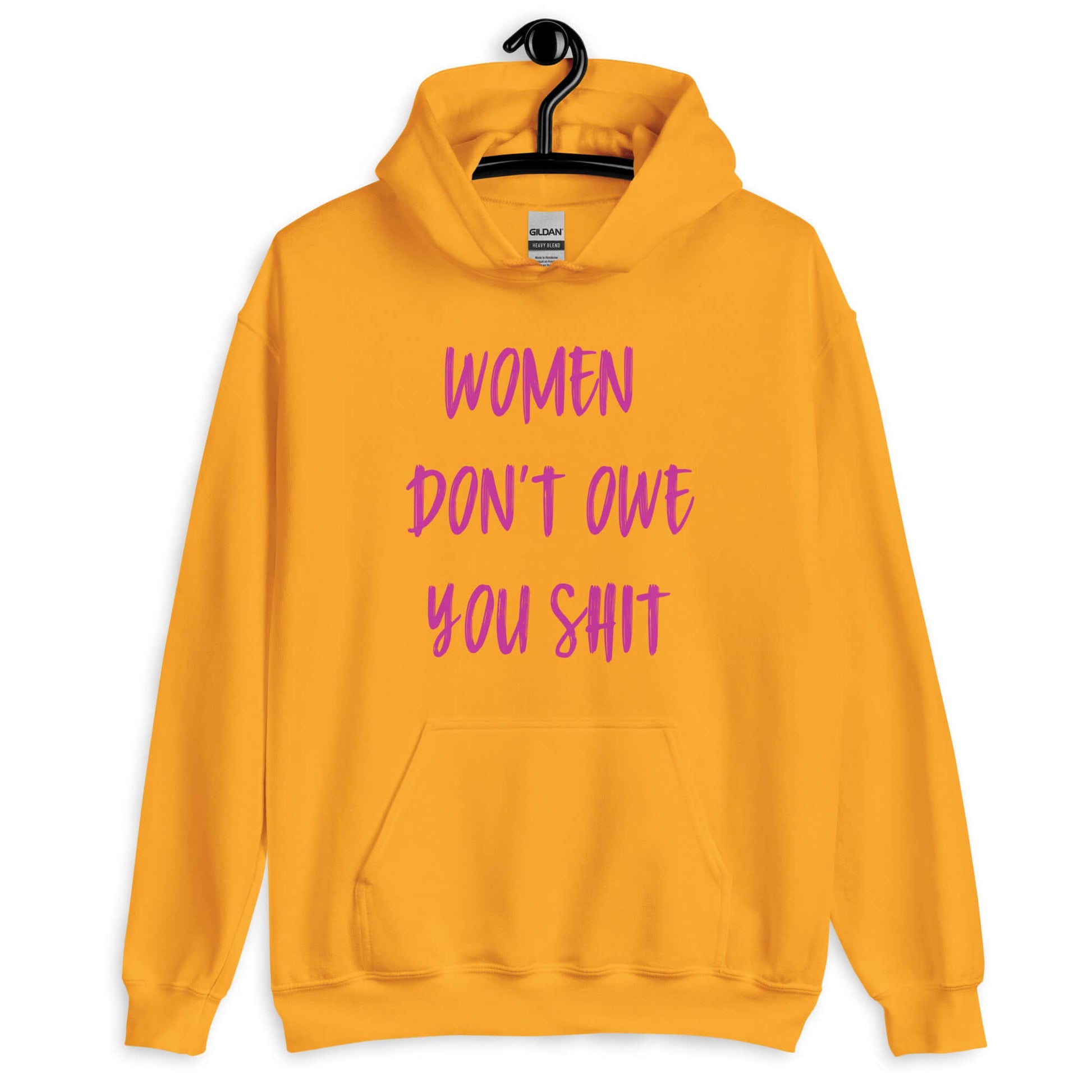 Golden yellow hoodie sweatshirt with the words Women don't owe you shit printed on the front in pink.