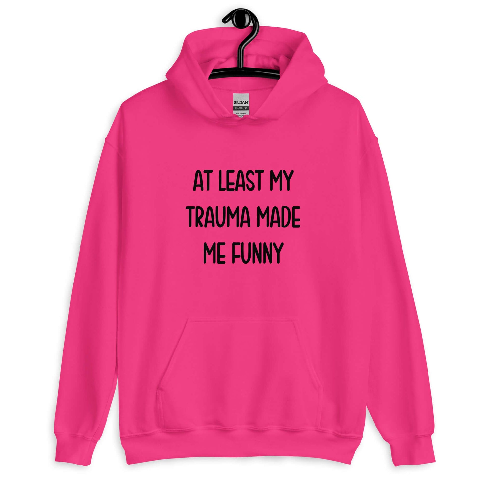 Heliconia pink hoodie sweatshirt with the words At least my trauma made me funny printed on the front.