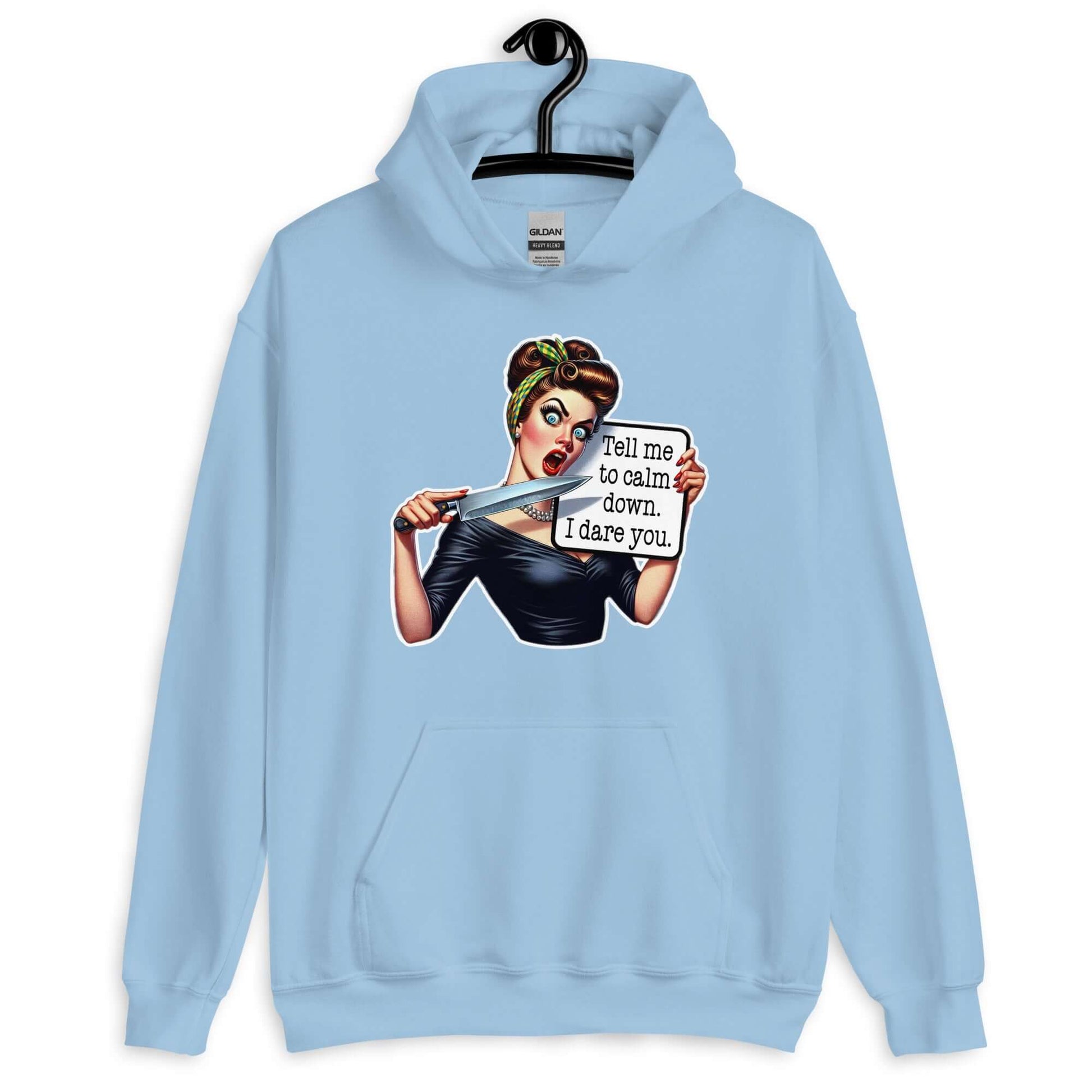 Light blue hoodie sweatshirt displayed on a hanger. The sweatshirt has a graphic of an angry looking retro woman holding a knife and a sign. The sign says Tell me to calm down I dare you. The graphic is printed on the front of the hoodie.