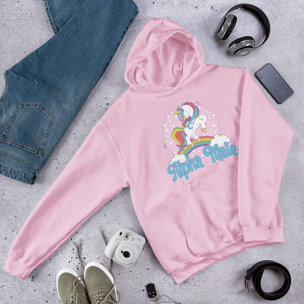 Light pink hoodie sweatshirt with funny pastel rainbow unicorn graphics and the words Alpha Male printed on the front.