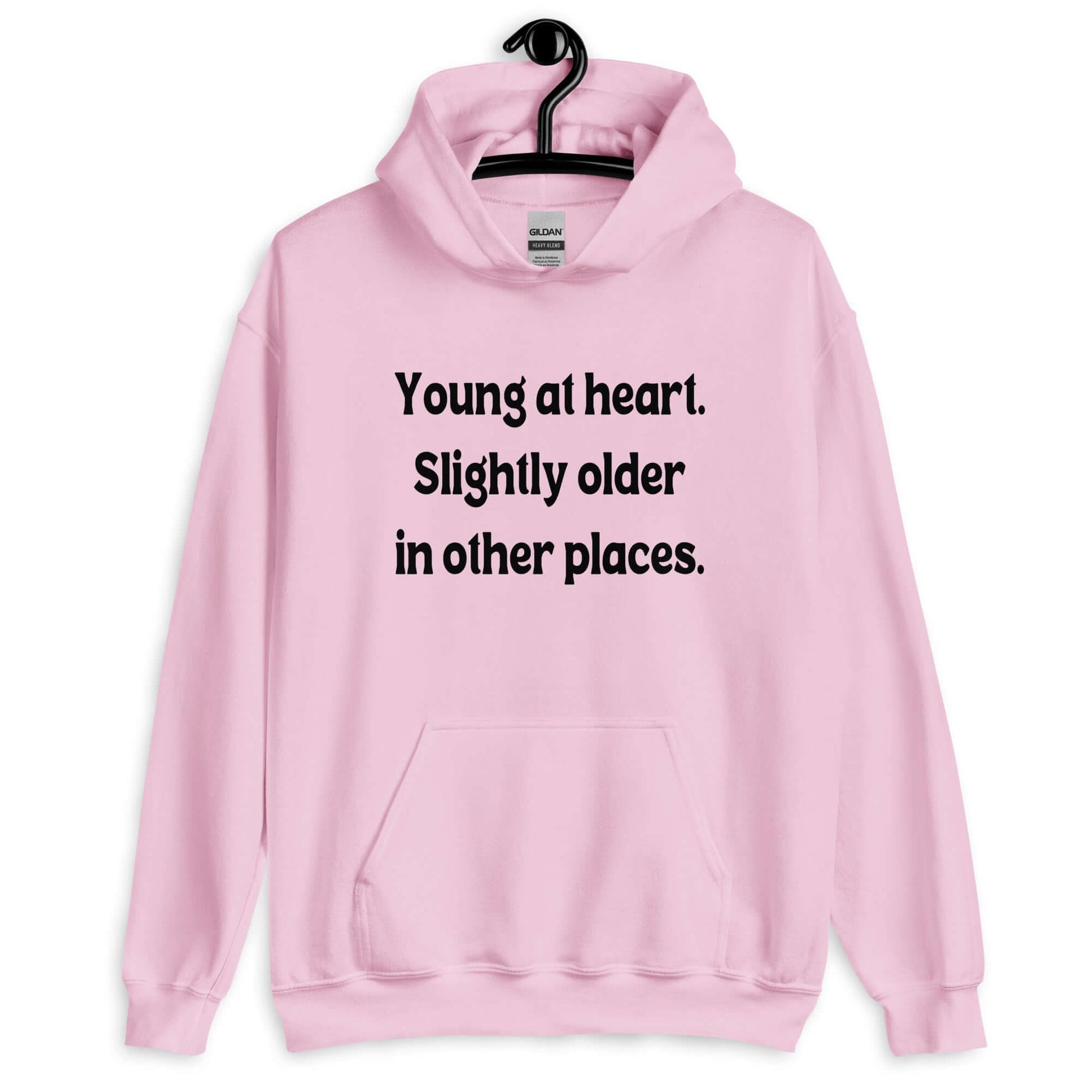 Light pink hoodie sweatshirt with the words Young at heart, slightly older in other places printed on the front.