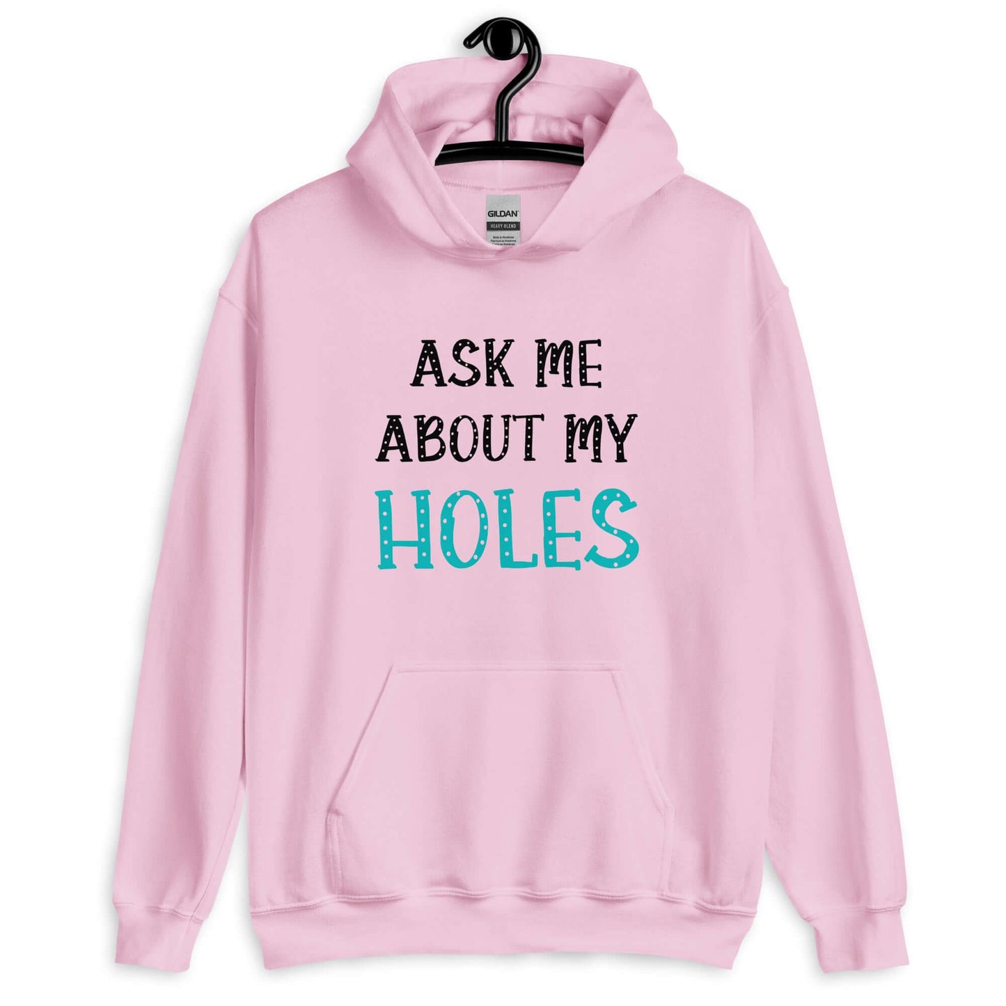 Light pink hoodie sweatshirt with the words Ask me about my holes printed on the front. The word holes in turquoise color and the rest of the text is black.