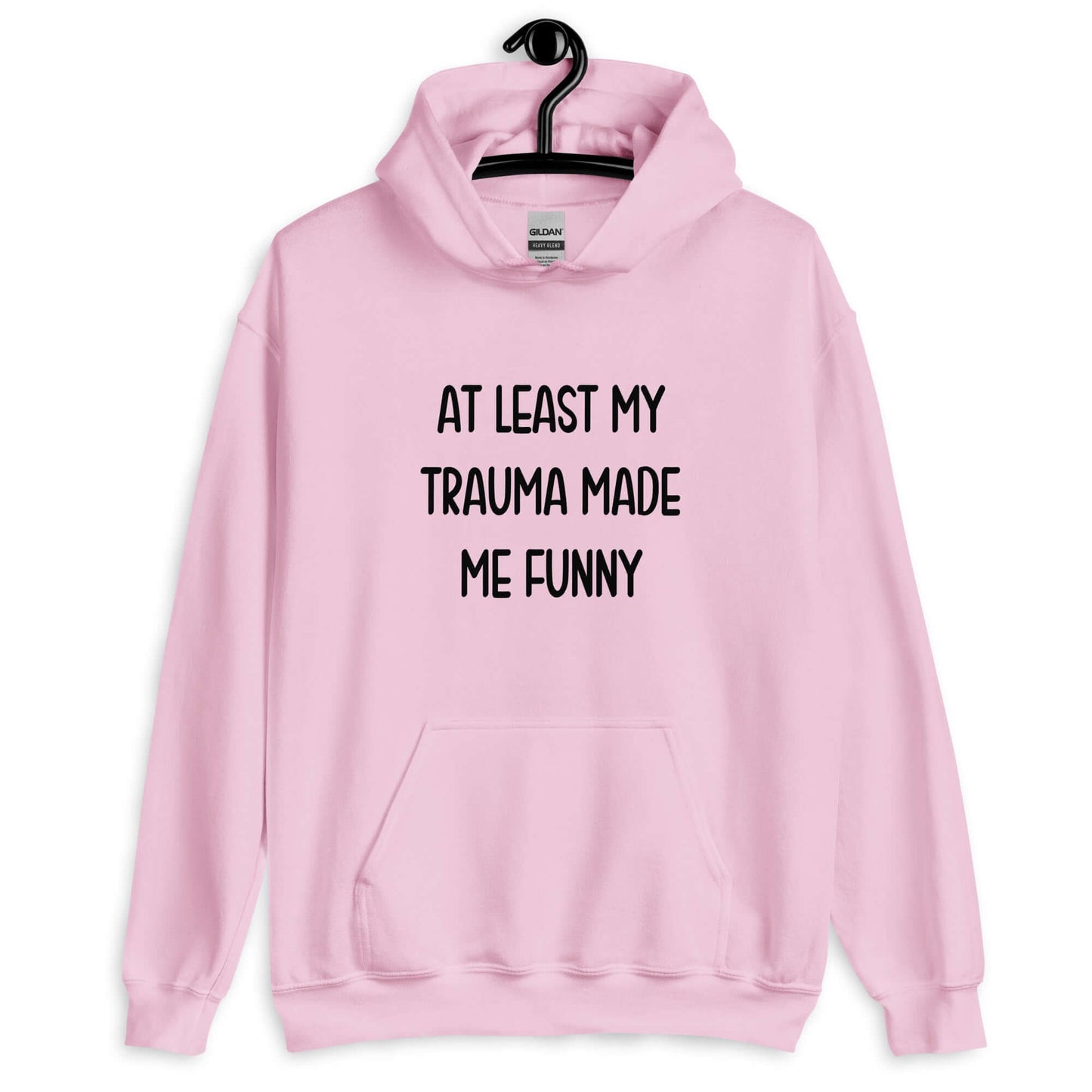 Light pink hoodie sweatshirt with the words At least my trauma made me funny printed on the front.