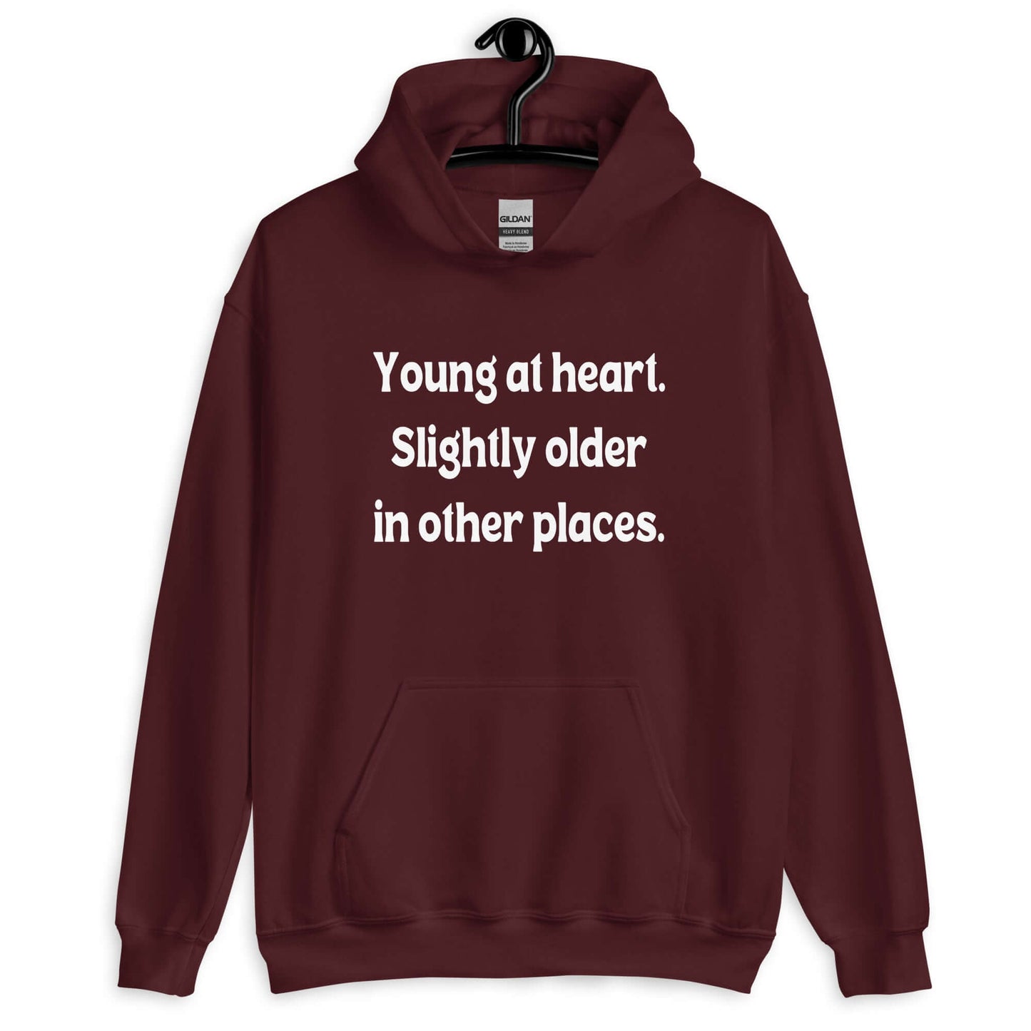 Maroon hoodie sweatshirt with the words Young at heart, slightly older in other places printed on the front.