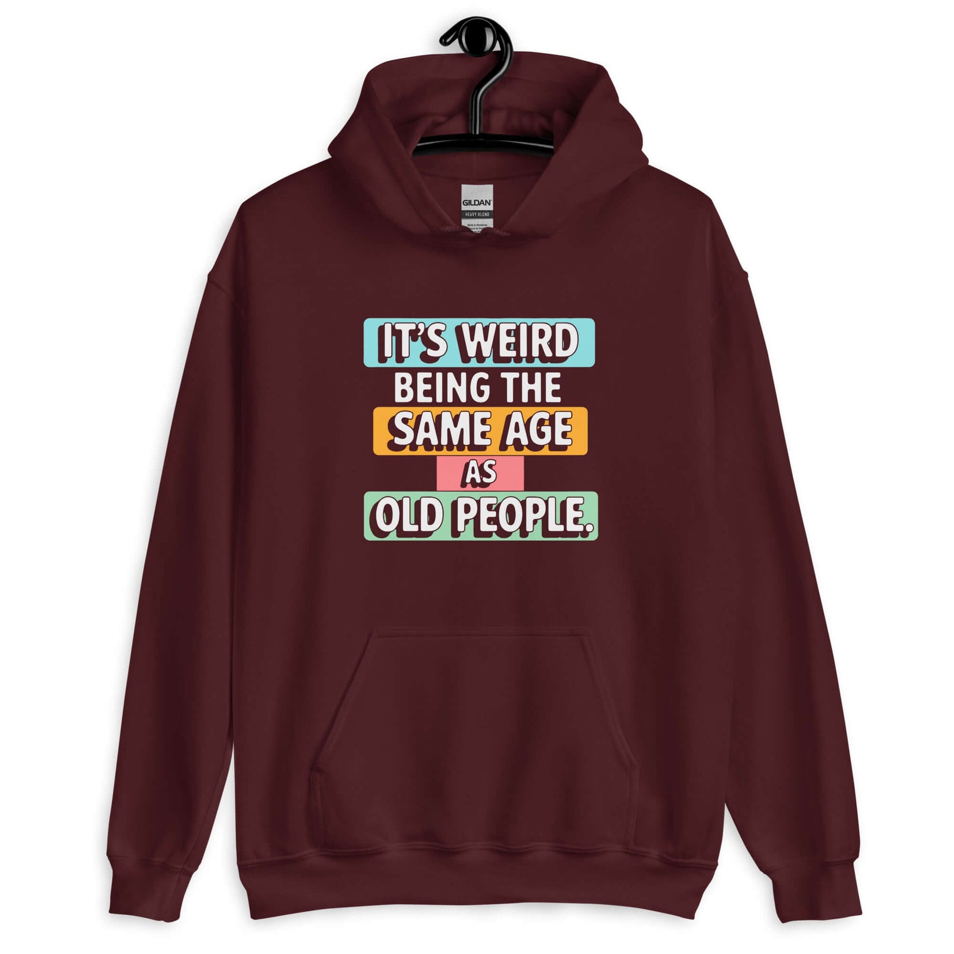 Maroon hoodie sweatshirt with colorful graphics that say It's weird being the same age as old people printed on the front.