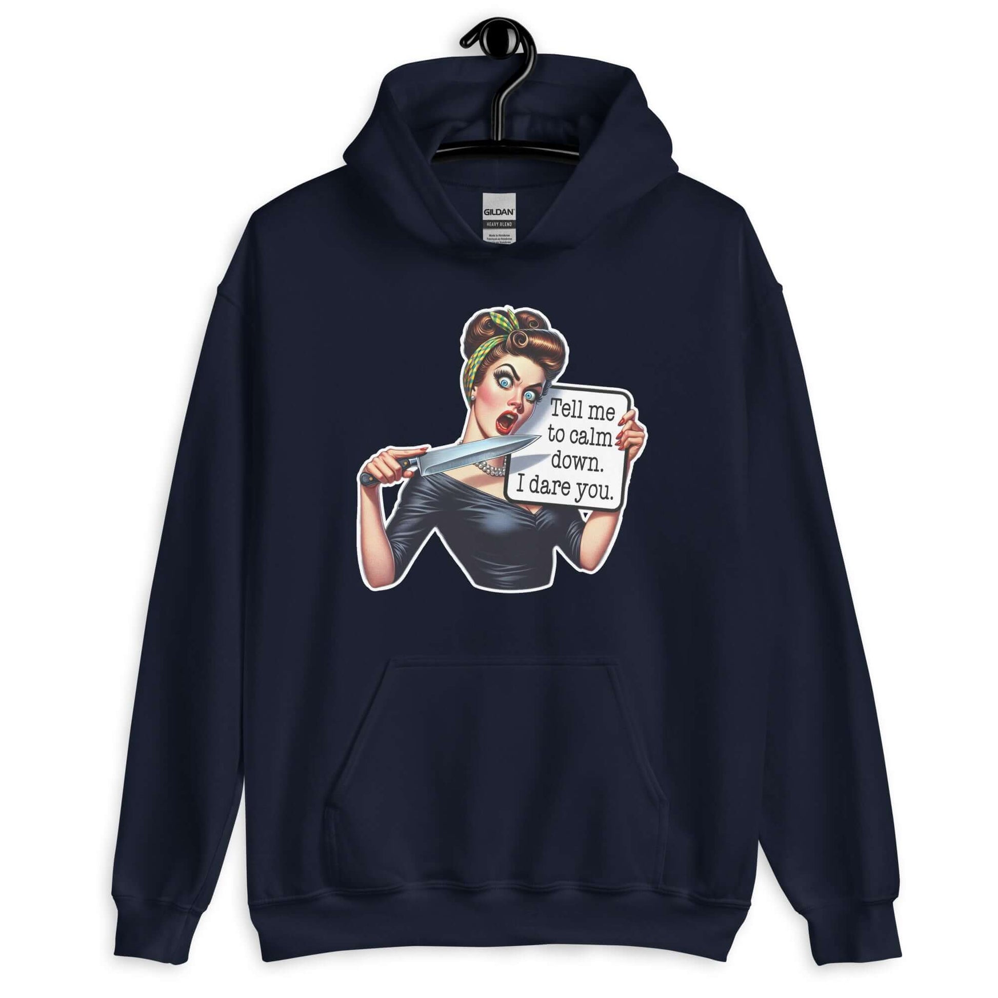 Navy blue hooded sweatshirt displayed on a hanger. The sweatshirt has a graphic of an angry looking retro woman holding a knife and a sign. The sign says Tell me to calm down I dare you. The graphic is printed on the front of the hoodie.