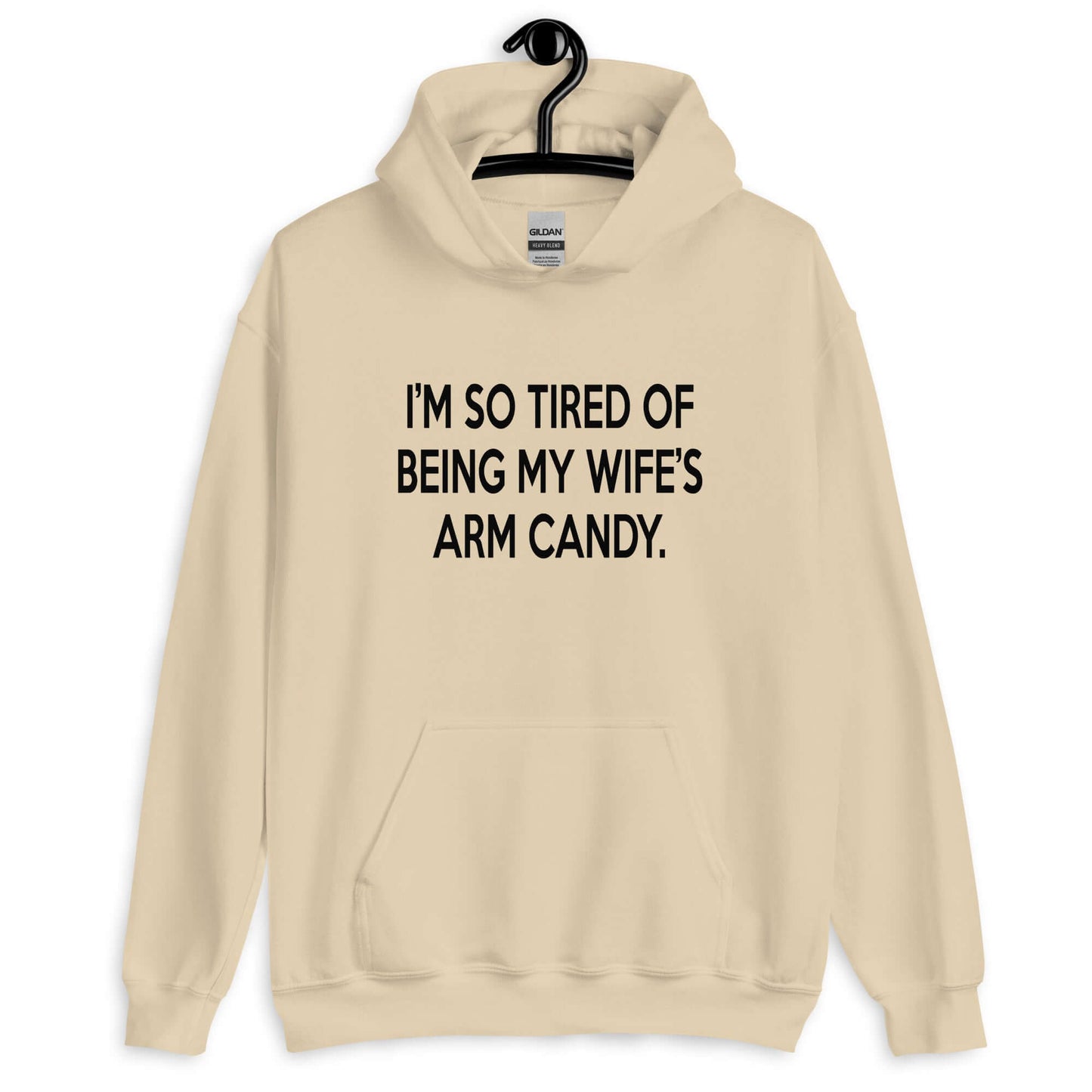 Sand color hoodie sweatshirt with the funny phrase I'm so tired of being my wife's arm candy printed on the front.