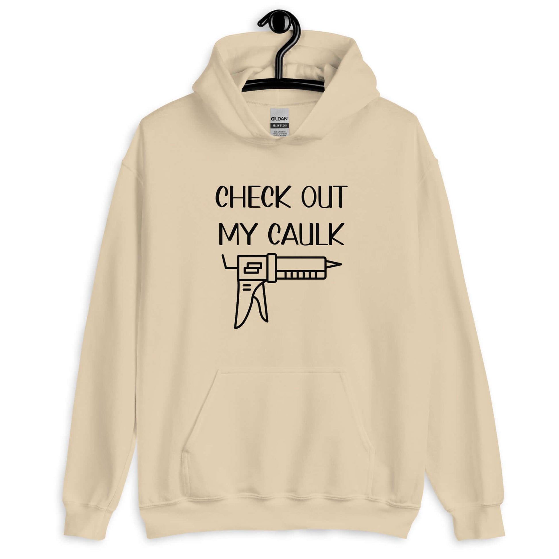 Sand hoodie sweatshirt with the pun phrase Check out my caulk with a line drawing image of a caulking gun printed on the front.