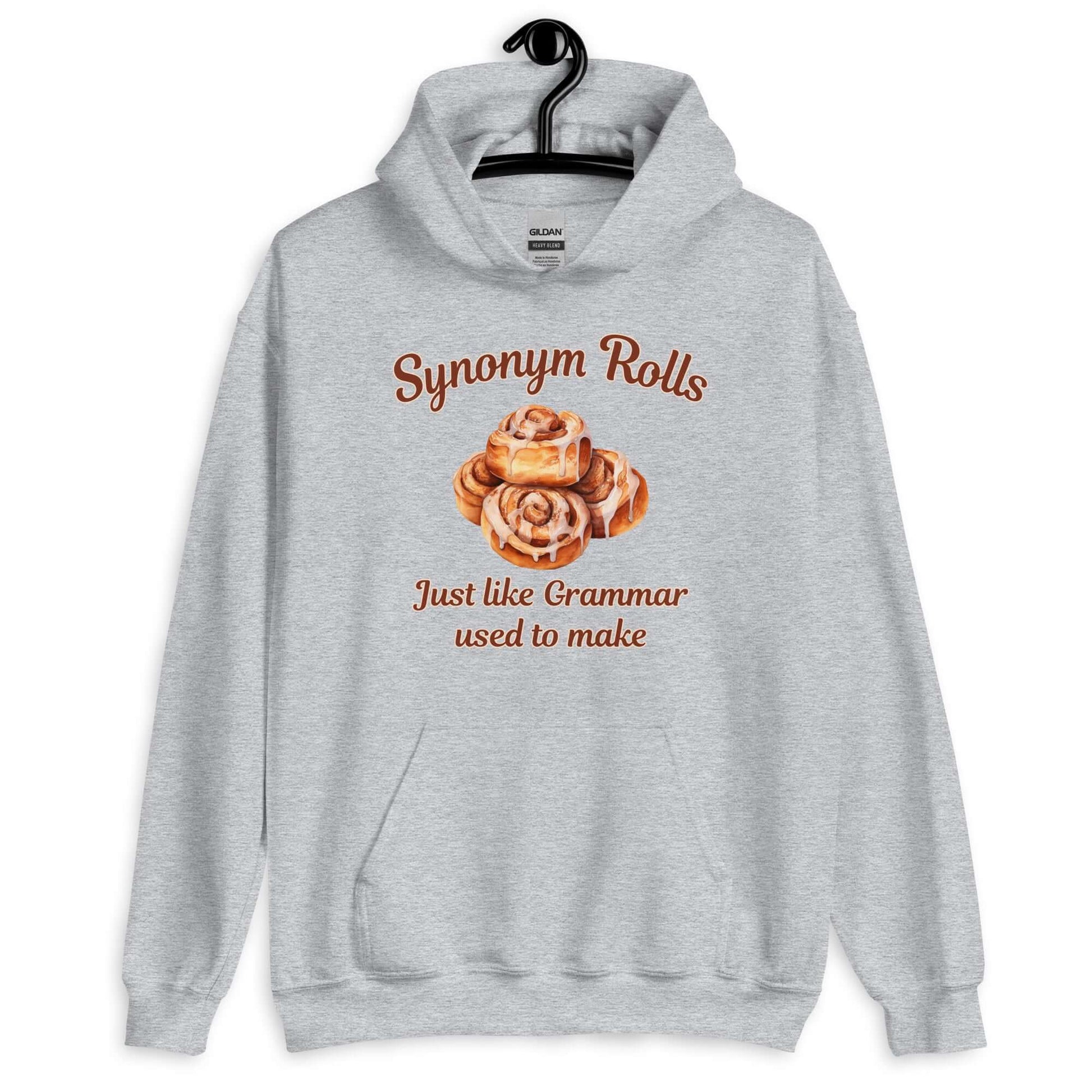 Sport grey hoodie sweatshirt with an image of cinnamon rolls and the pun phrase Synonym rolls Just like Grammar used to make printed on the front.