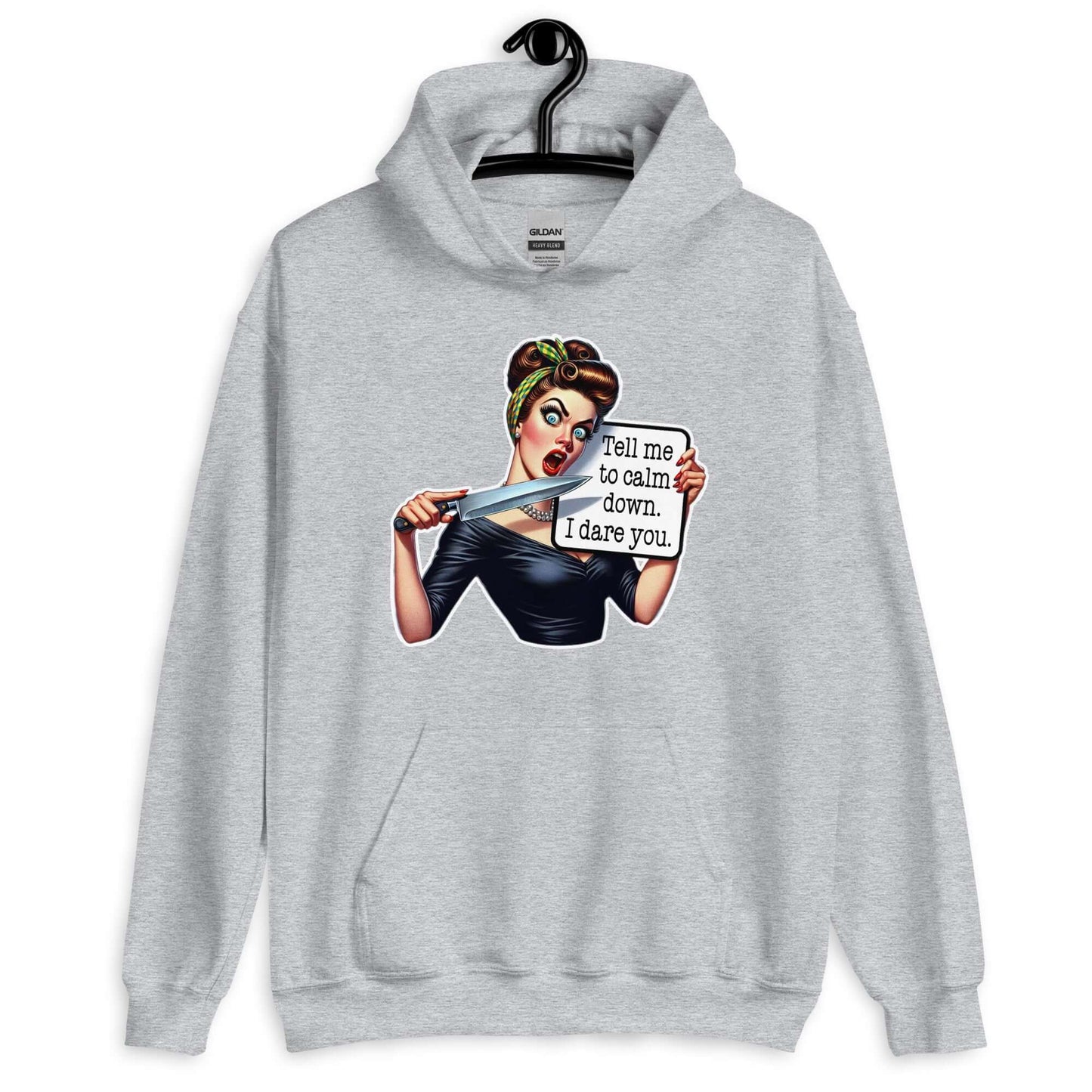 Light grey hooded sweatshirt displayed on a hanger. The sweatshirt has a graphic of an angry looking retro woman holding a knife and a sign. The sign says Tell me to calm down I dare you. The graphic is printed on the front of the hoodie.