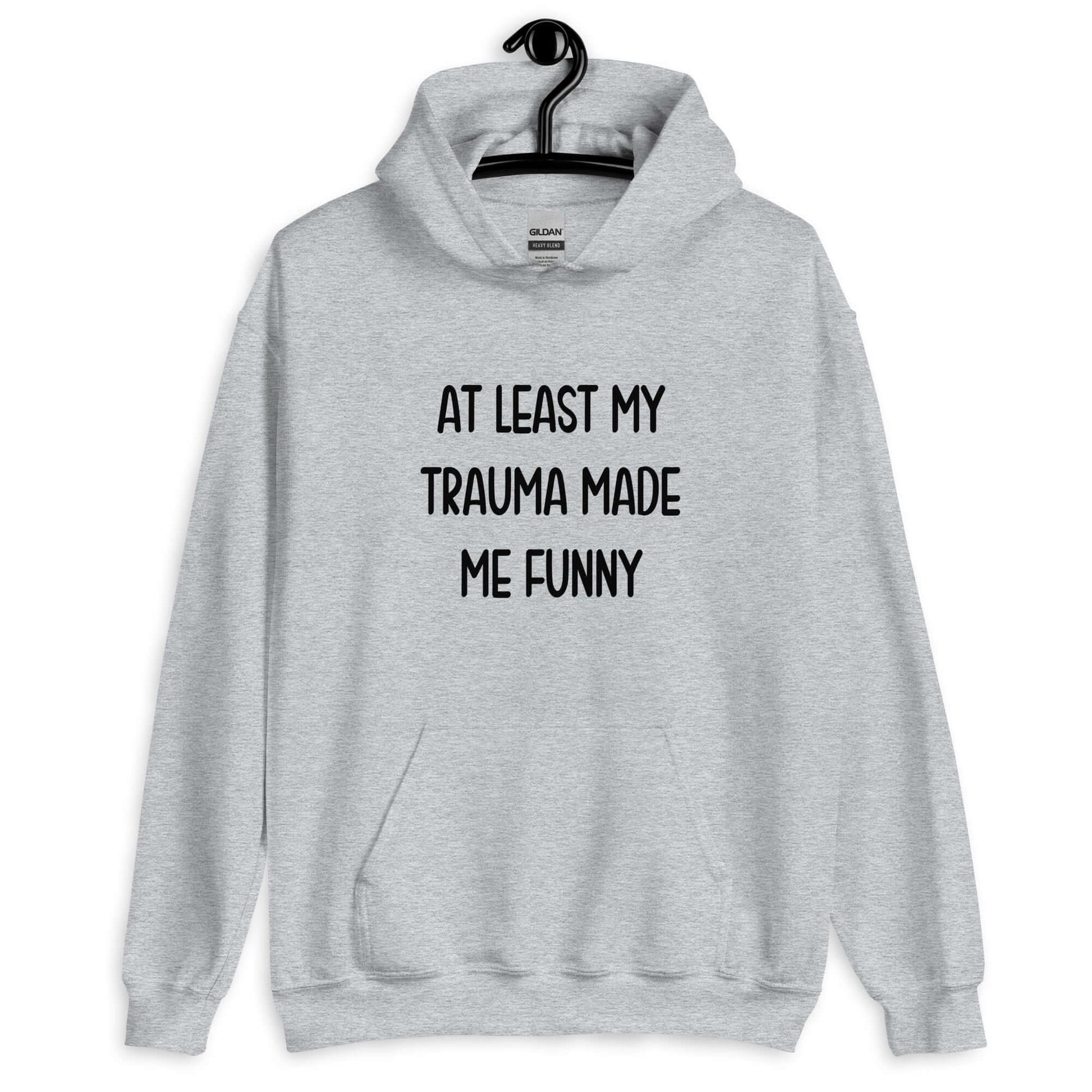 Sport grey hoodie sweatshirt with the words At least my trauma made me funny printed on the front.