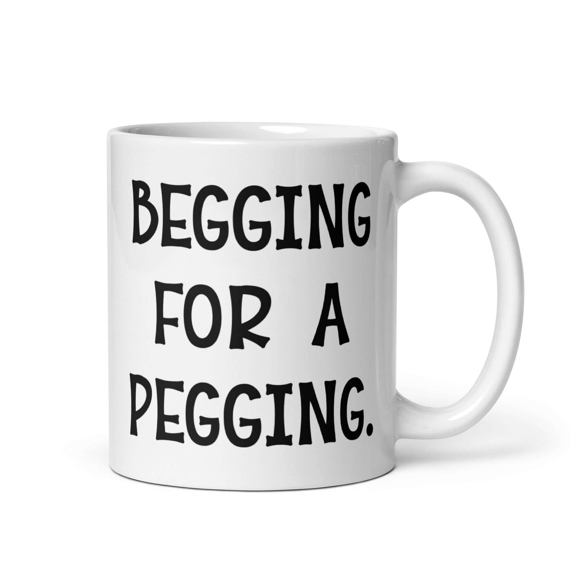 White ceramic coffee mug with the words Begging for a pegging printed on both sides.