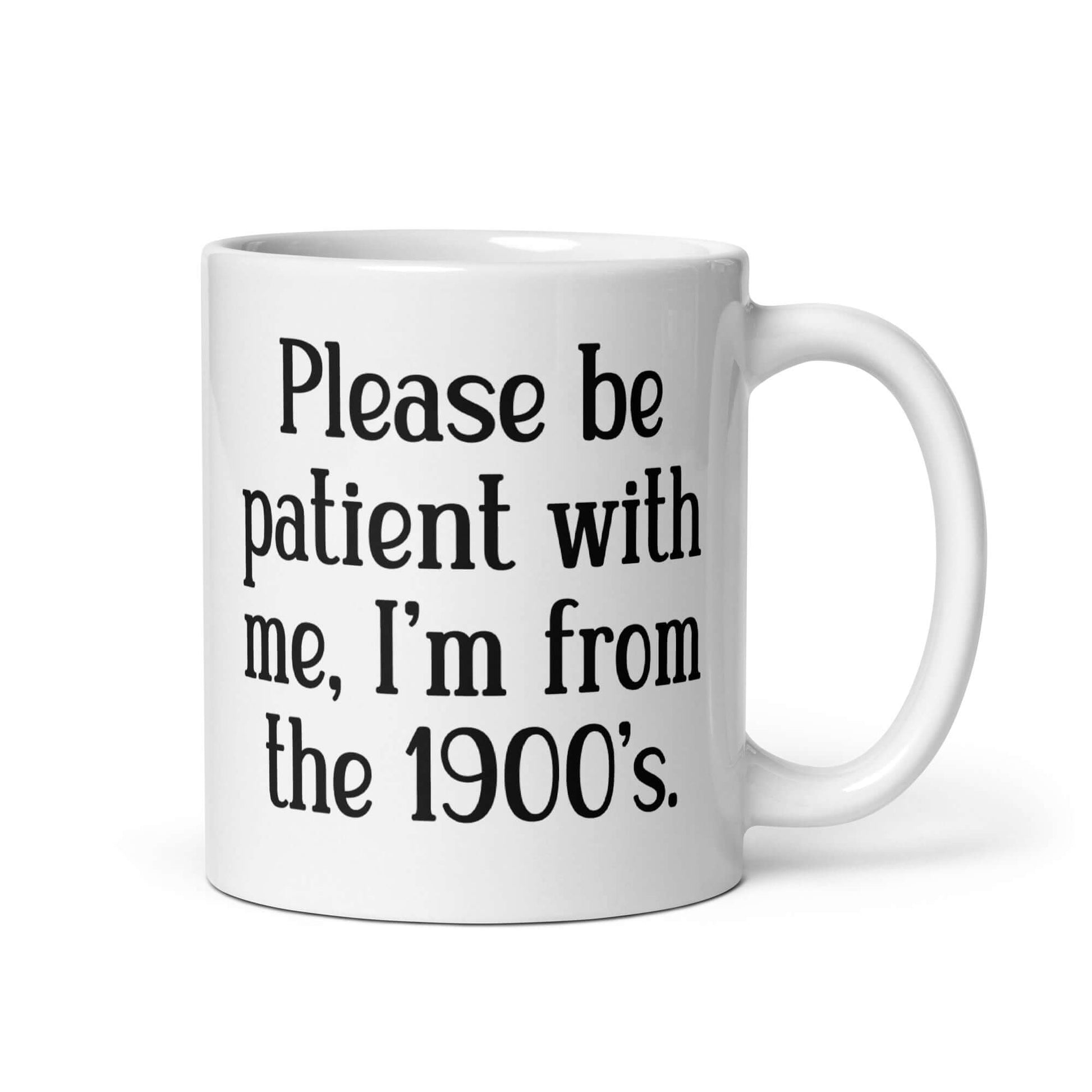 11 ounce white ceramic mug the phrase Please be patient with me, I'm from the 1900s printed on both sides.