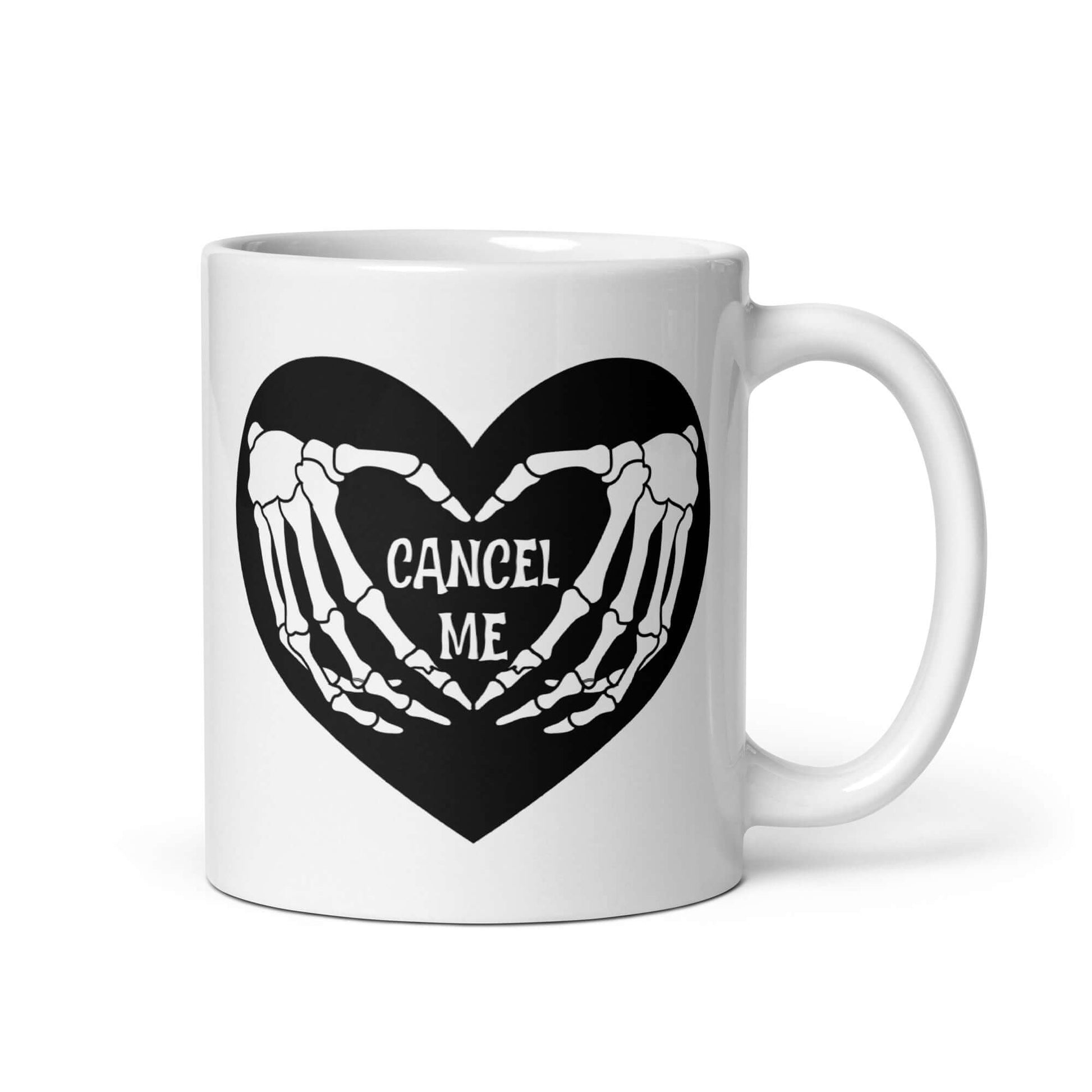 White ceramic mug with a black heart and skeleton hands making a heart shape. The words Cancel Me are inside of the heart. The graphics are printed on both sides of the mug.