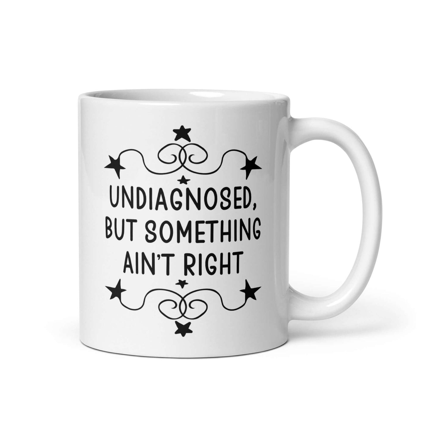 11 ounce white ceramic mug with the phrase Undiagnosed, but something ain't right printed on both sides.