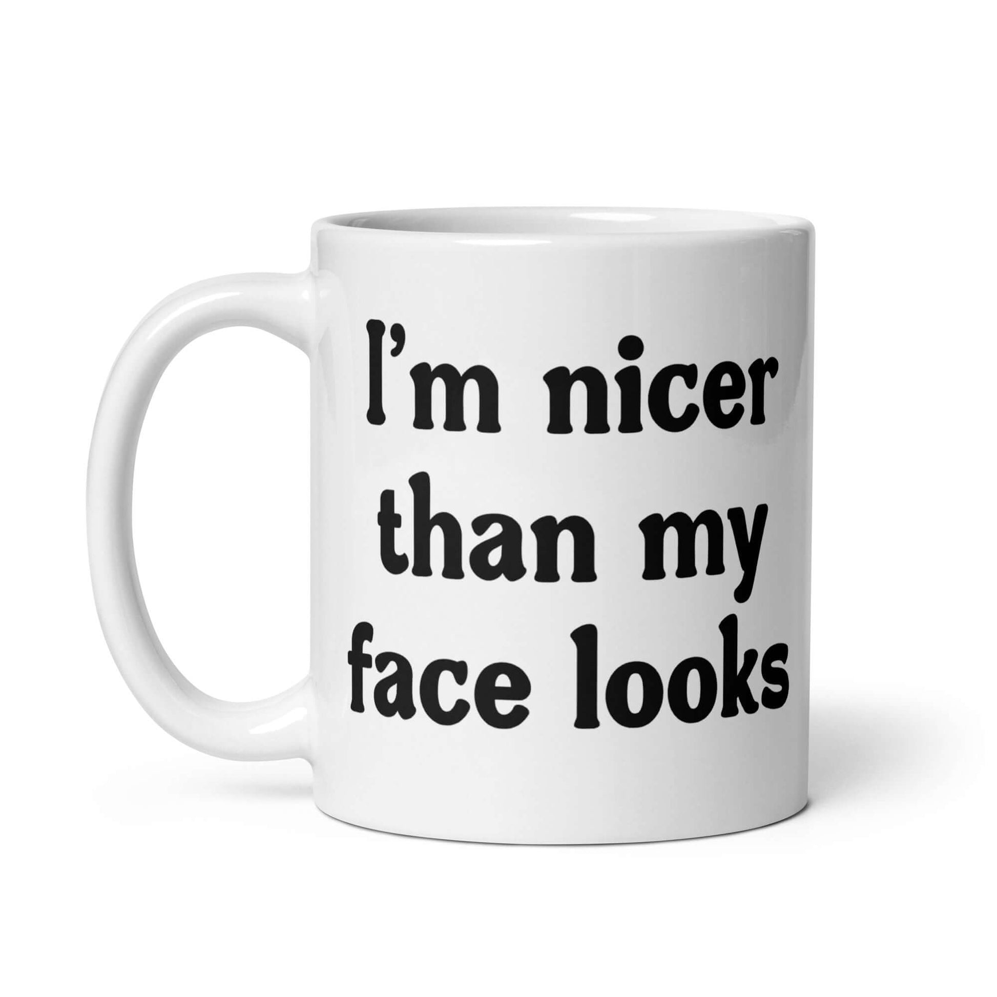 White ceramic coffee mug that says I'm nicer than my face looks printed on both sides of the mug.