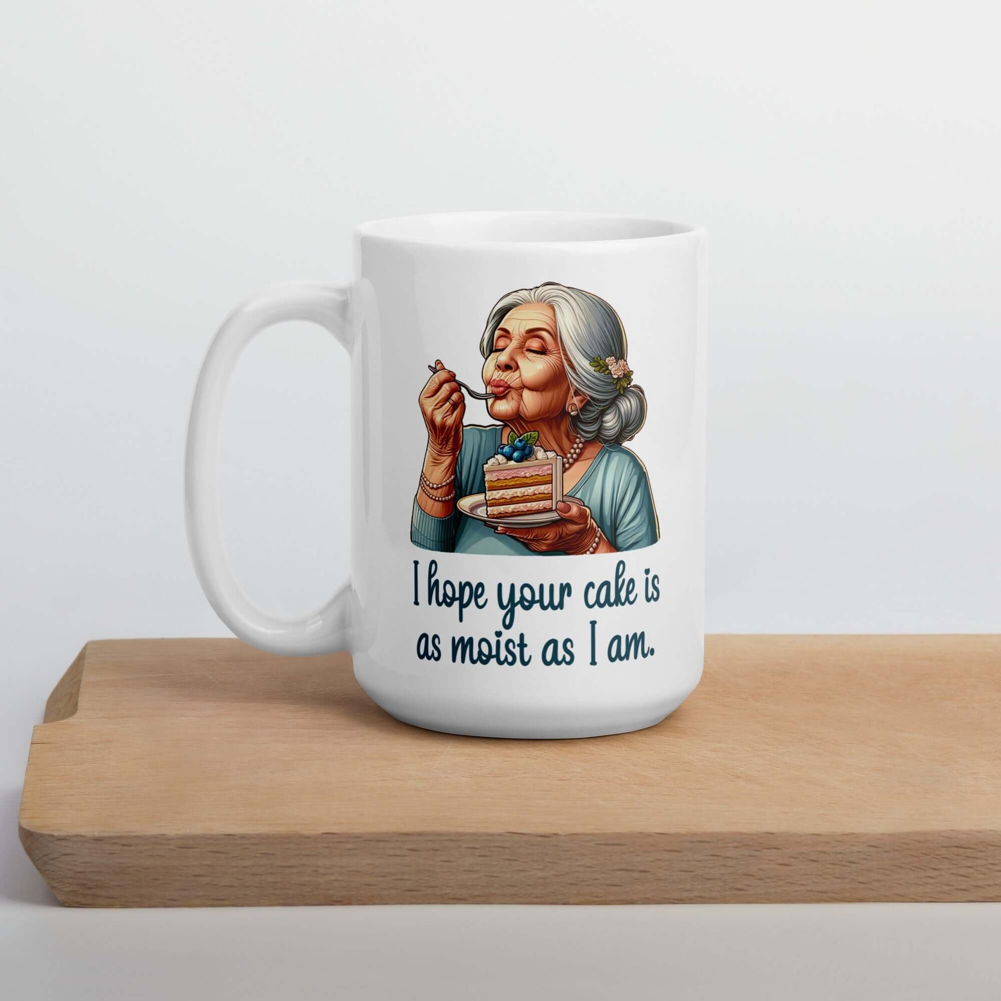 White ceramic coffee mug with an image of grey haired older woman enjoying a bite of a piece of cake with the words I hope your cake is as moist as I am printed on both sides.