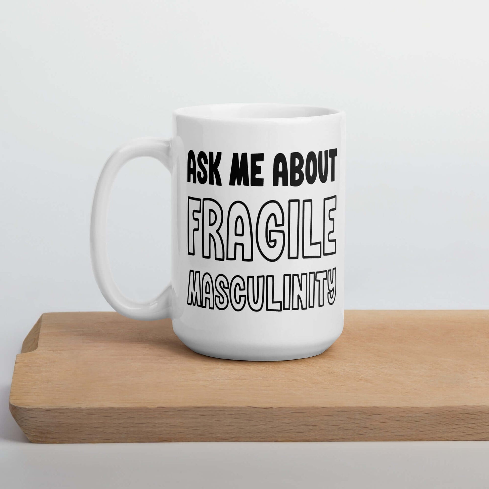 White ceramic mug with the phrase Ask me about fragile masculinity printed on both sides of the mug.