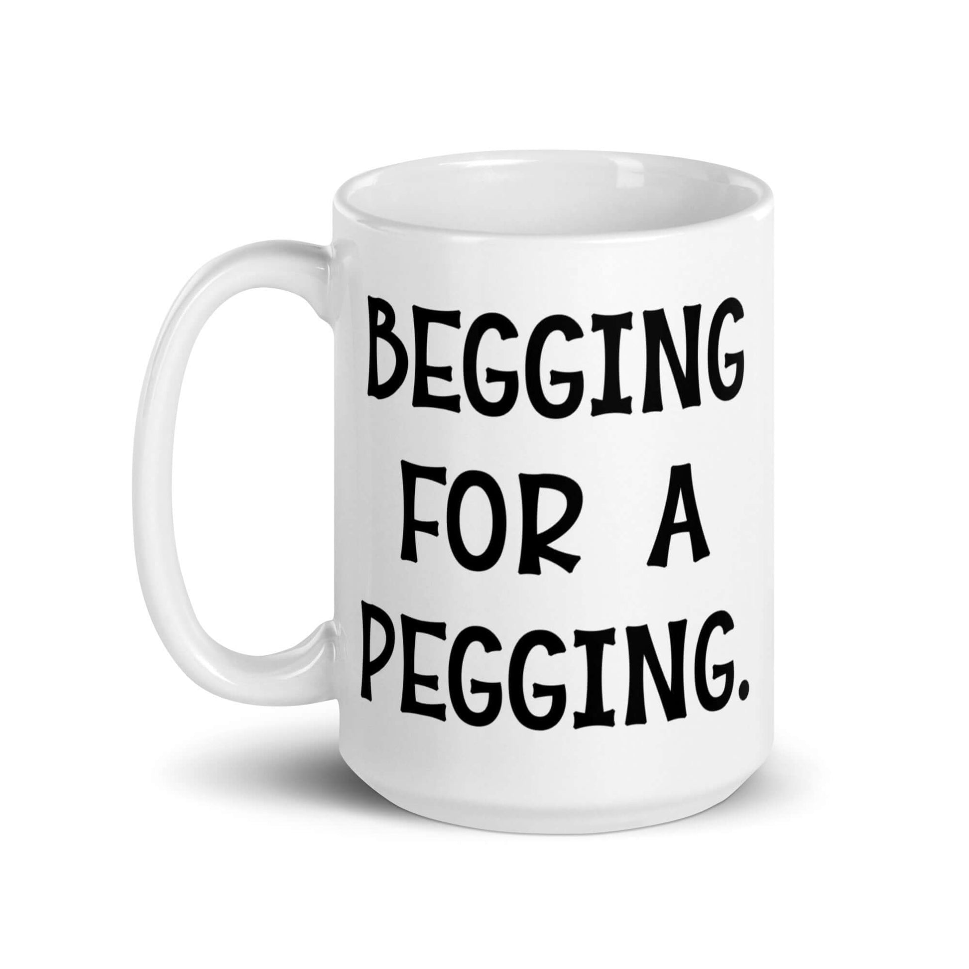 White ceramic coffee mug with the words Begging for a pegging printed on both sides.