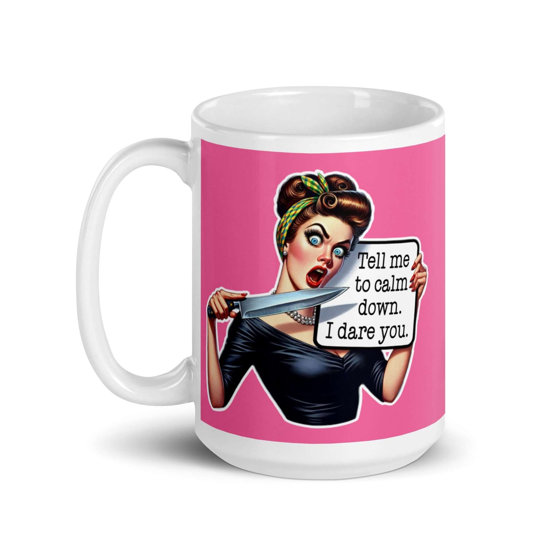 White ceramic coffee mug with pink color wrapped around. The mug has a graphic of an angry looking retro woman holding a knife and a sign. The sign says Tell me to calm down I dare you. The graphic is printed on both sides of the mug.