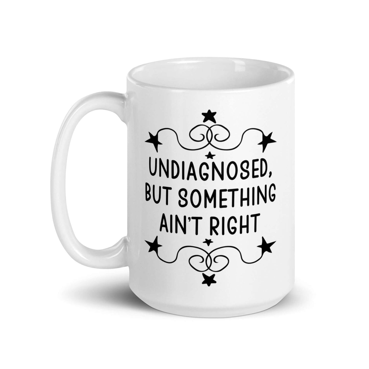 15 ounce white ceramic mug with the phrase Undiagnosed, but something ain't right printed on both sides.