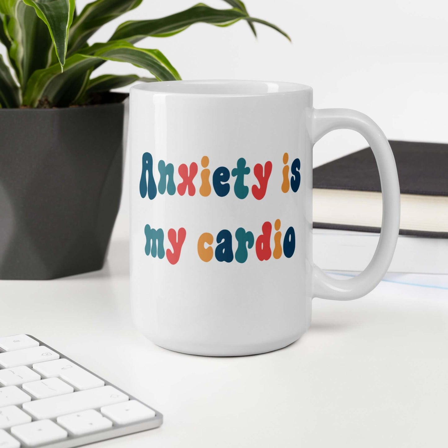 White ceramic mug with the phrase Anxiety is my cardio printed in multiple colors on both sides of the mug.