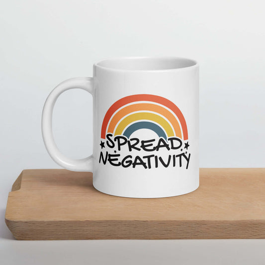 White ceramic mug with a graphic of a rainbow and the words Spread negativity printed on both sides.