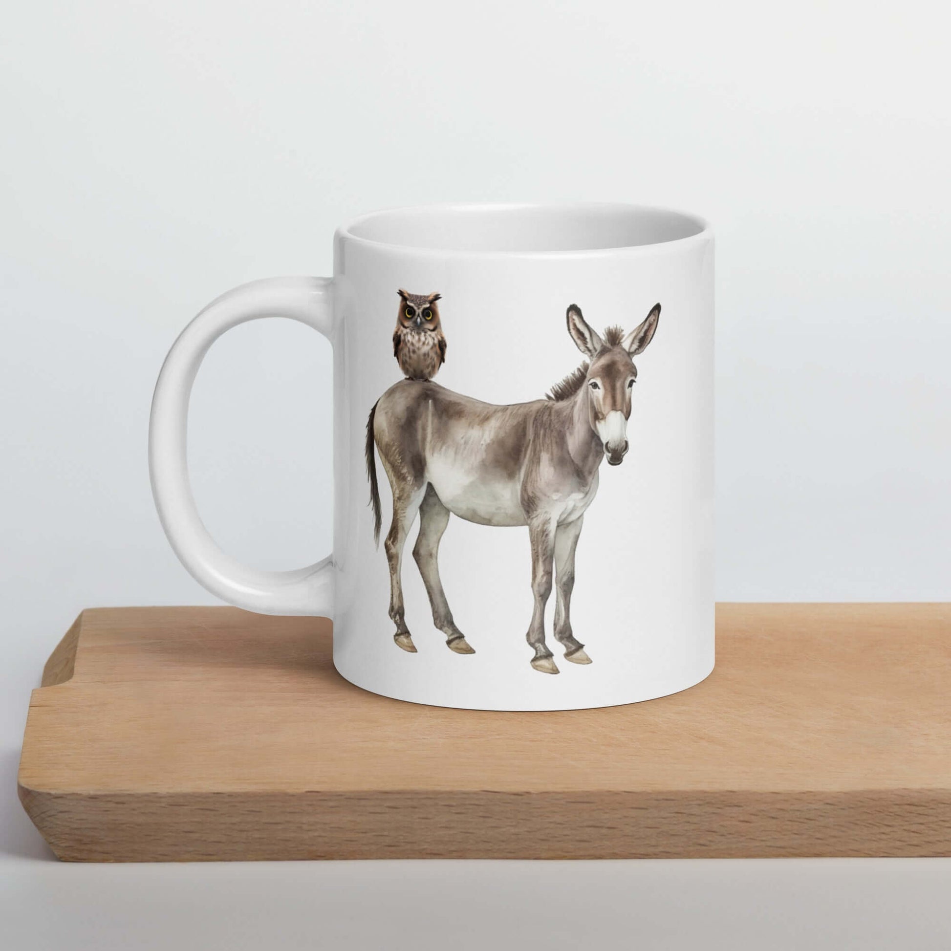 White ceramic coffee mug with an image of a donkey with wise owl sitting on it printed on both sides of the mug.