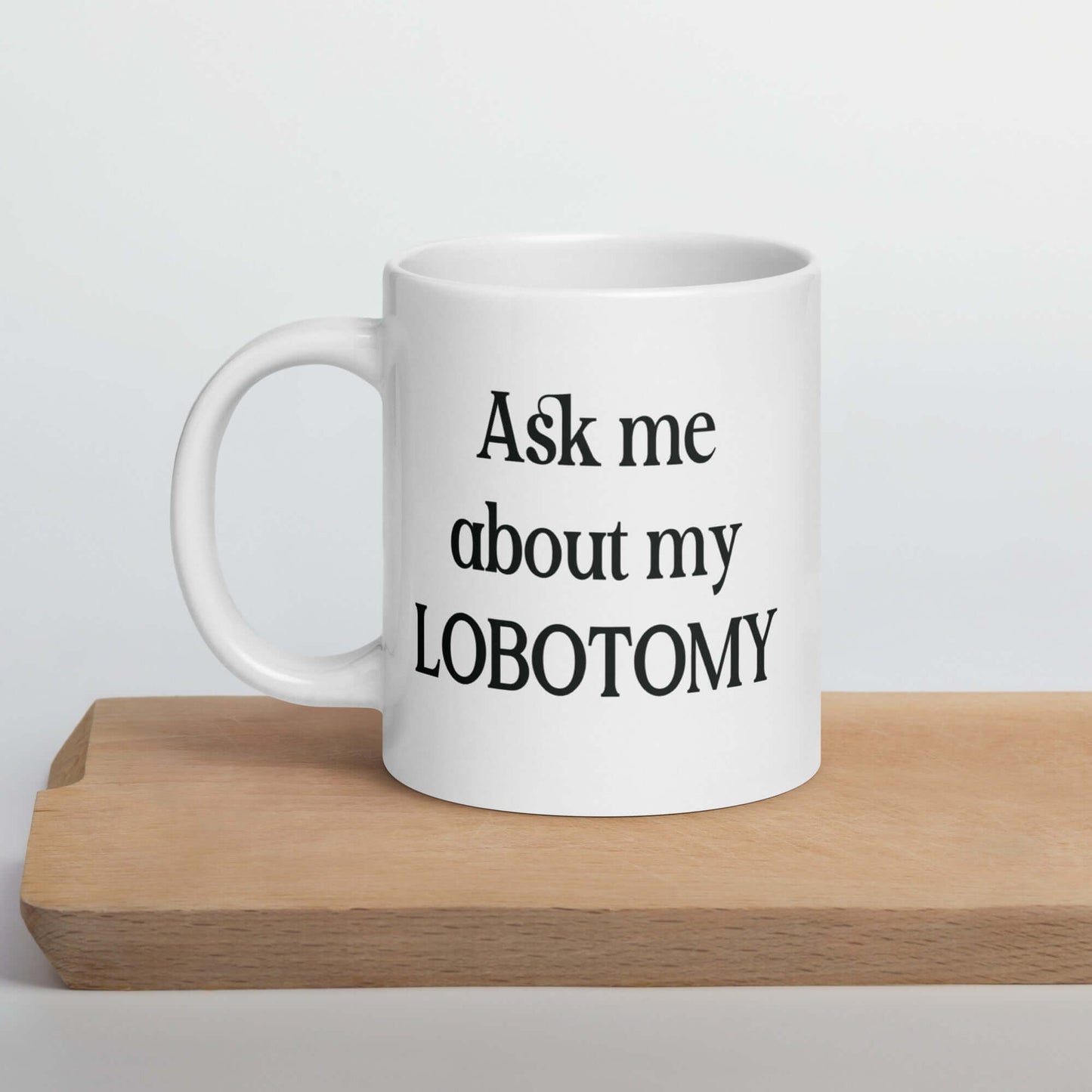 White ceramic mug with the phrase Ask me about my lobotomy printed on both sides of the mug.