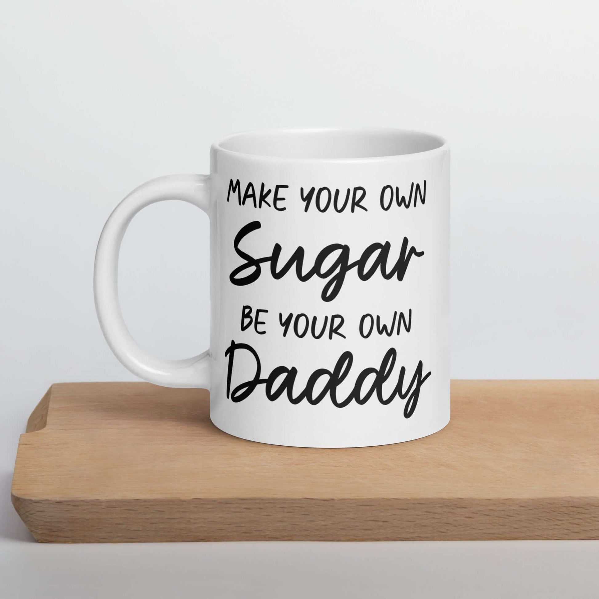 White ceramic coffee mug with the phrase Make your own sugar Be your own Daddy printed on both sides.