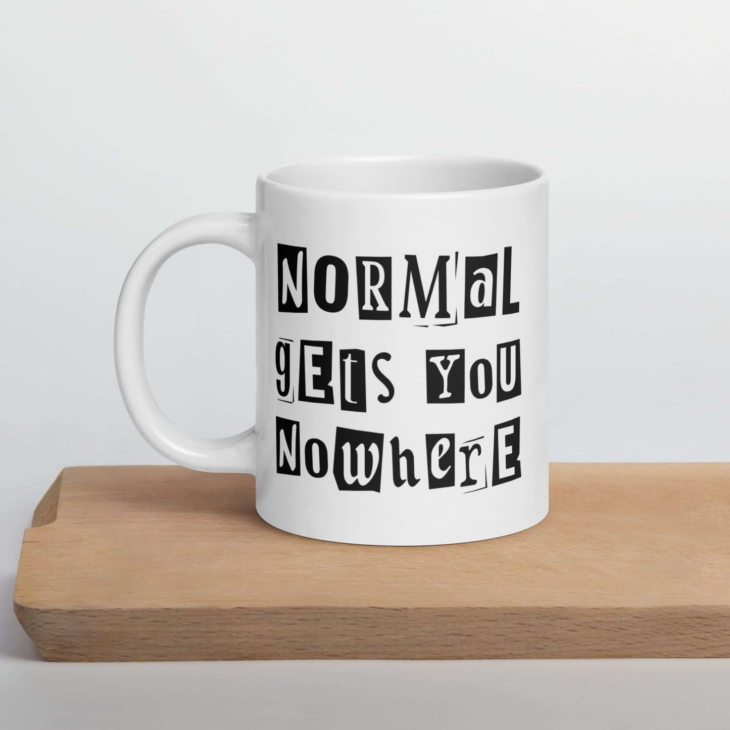 White ceramic coffee mug with the phrase Normal gets you nowhere printed on both sides.