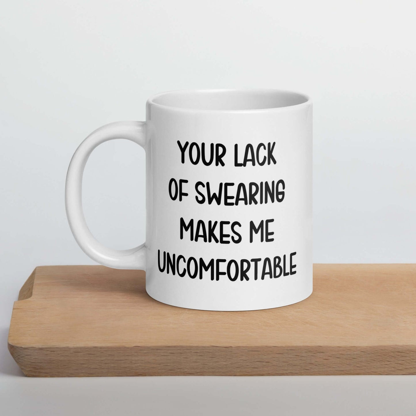 White ceramic mug with the phrase Your lack of swearing makes me uncomfortable printed on both sides.