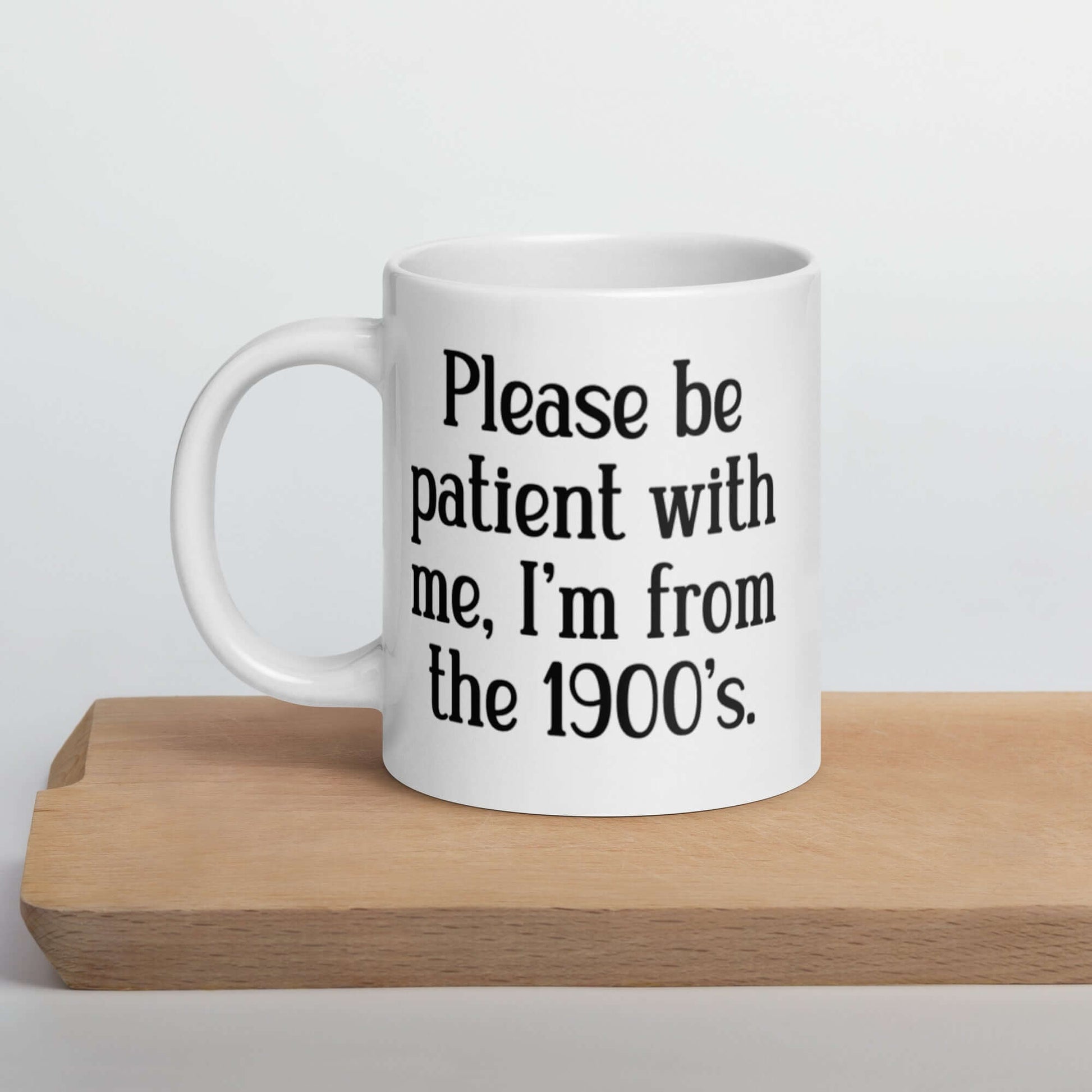 20 ounce white ceramic mug the phrase Please be patient with me, I'm from the 1900s printed on both sides.