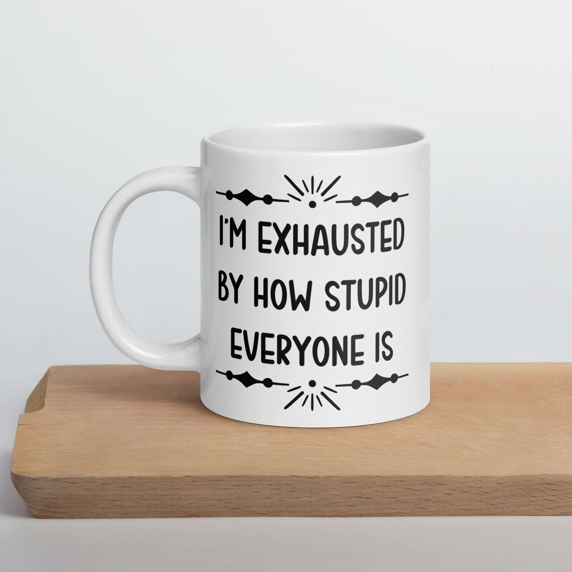 20 ounce white ceramic coffee mug with the phrase I'm exhausted by how stupid everyone is printed on both sides of the mug.