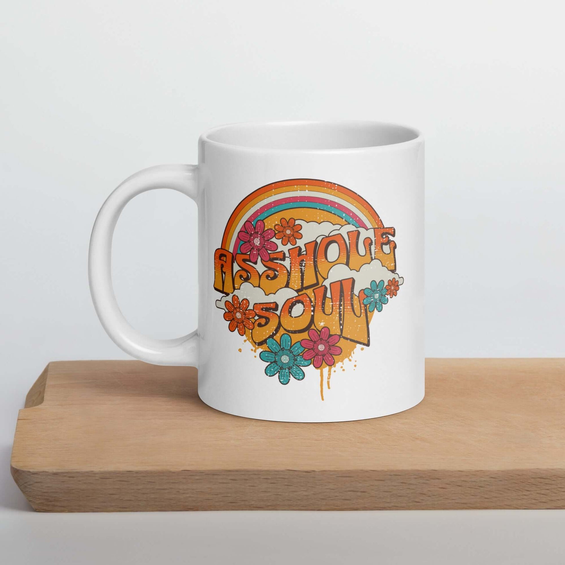 White ceramic mug with retro looking distressed rainbow graphic and the words Asshole Soul. The graphics are printed on both sides of the mug.