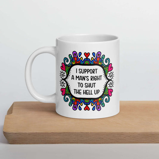 White ceramic mug with a colorful doodle graphic and the words I support a man's right to shut the hell up. The design is printed on both sides of the mug.