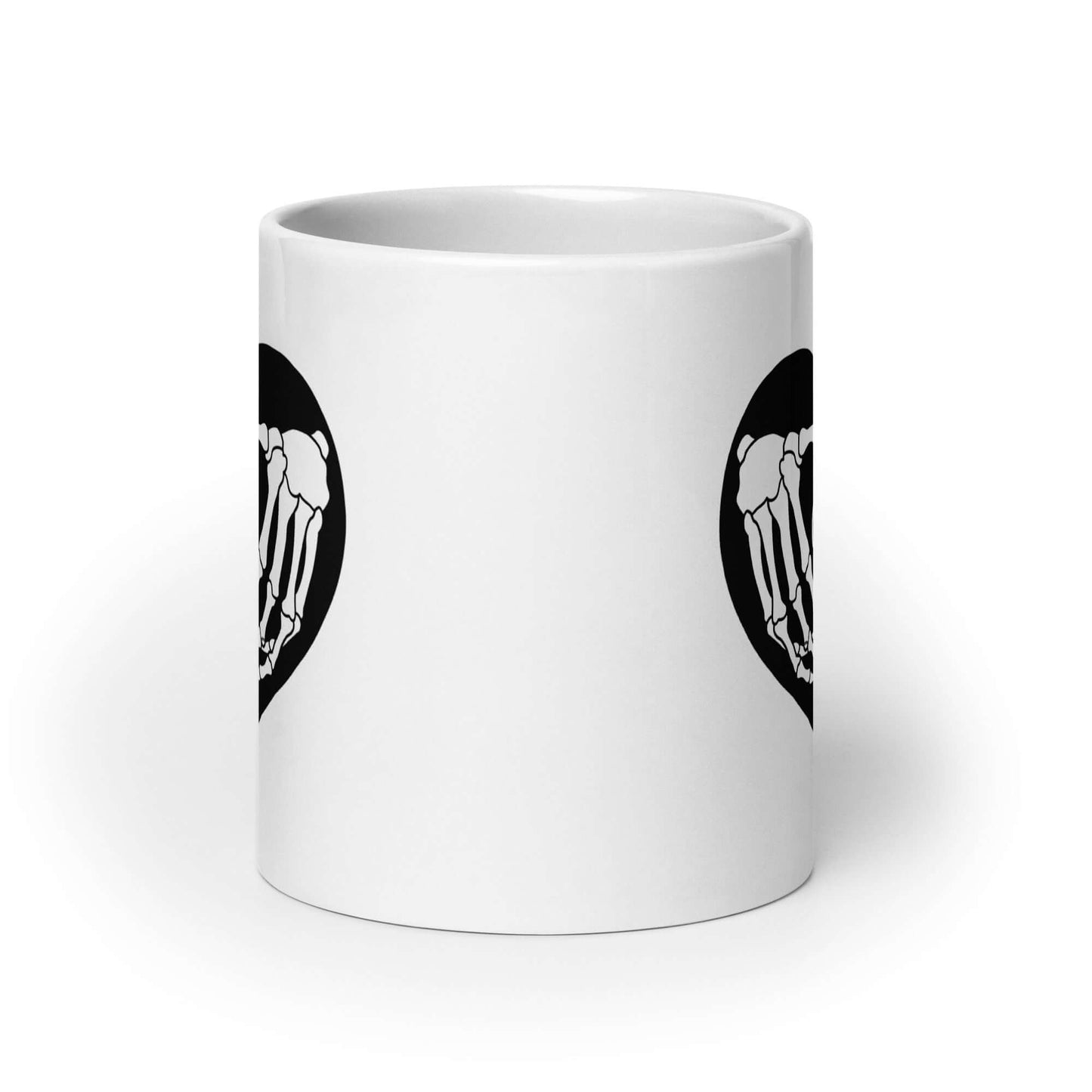 White ceramic mug with a black heart and skeleton hands making a heart shape. The words Cancel Me are inside of the heart. The graphics are printed on both sides of the mug.