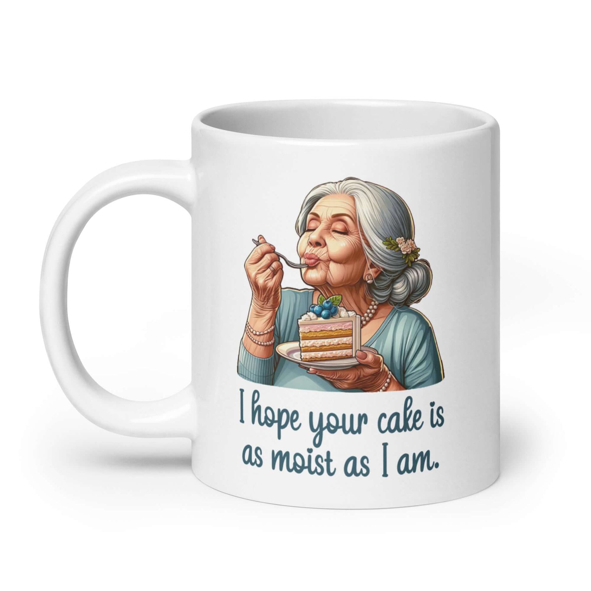 White ceramic coffee mug with an image of grey haired older woman enjoying a bite of a piece of cake with the words I hope your cake is as moist as I am printed on both sides.