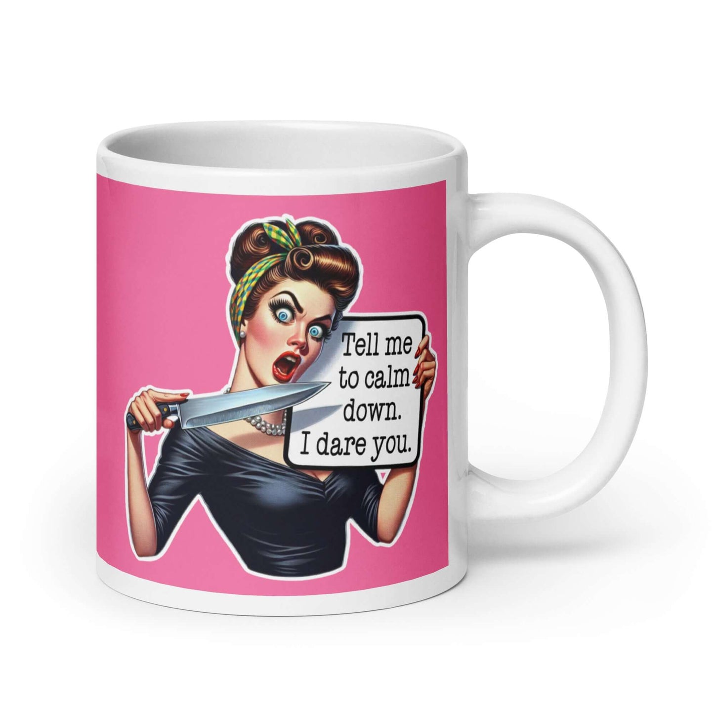 White ceramic coffee mug with pink color wrapped around. The mug has a graphic of an angry looking retro woman holding a knife and a sign. The sign says Tell me to calm down I dare you. The graphic is printed on both sides of the mug.