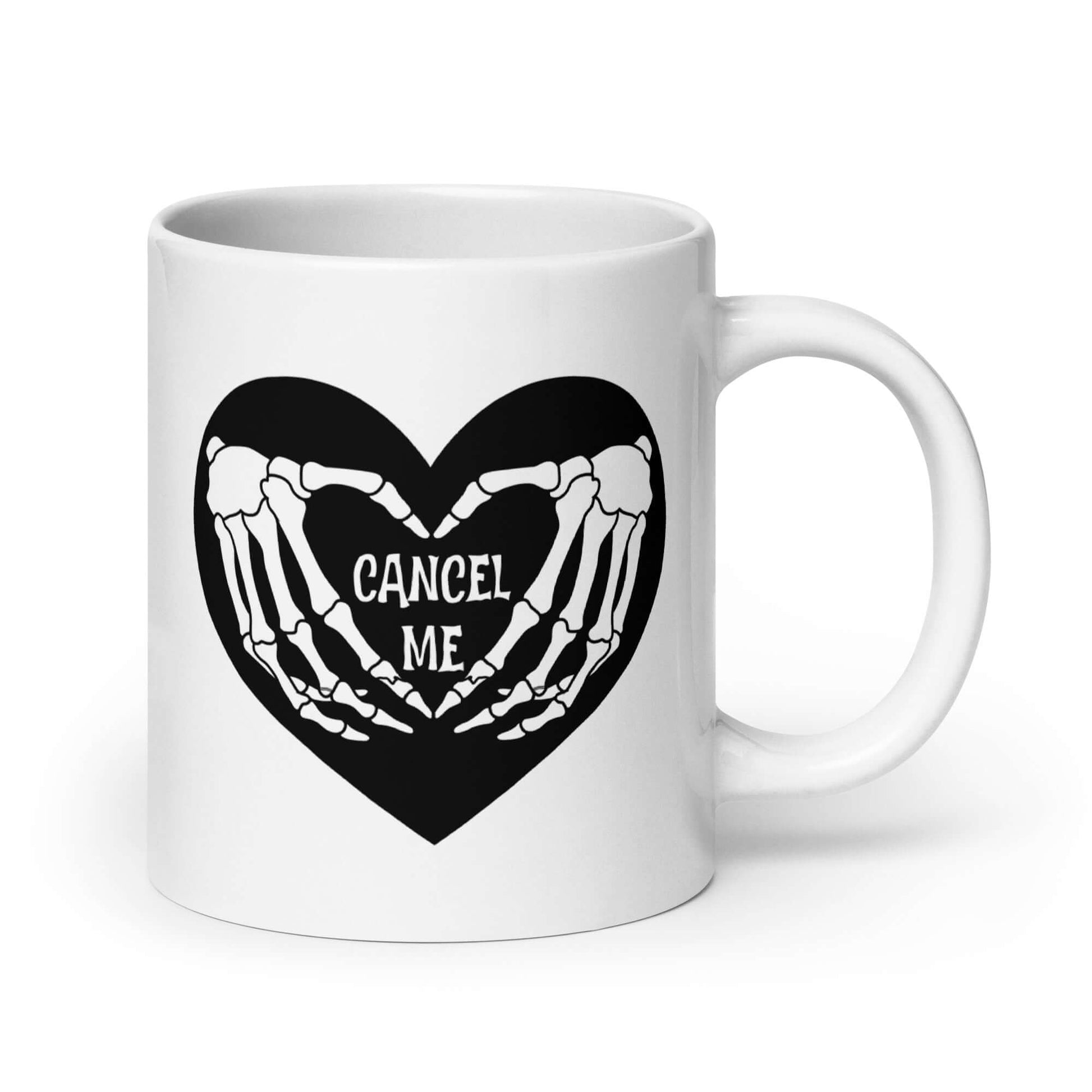 White ceramic mug with a black heart and skeleton hands making a heart shape. The words Cancel Me are inside of the heart. The graphics are printed on both sides of the mug.