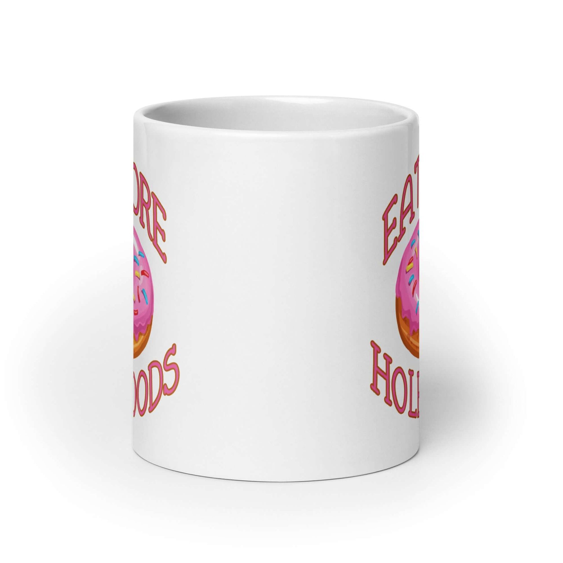 White coffee mug with an image of a donut with pink icing and sprinkles and the words Eat more hole foods printed on both sides.