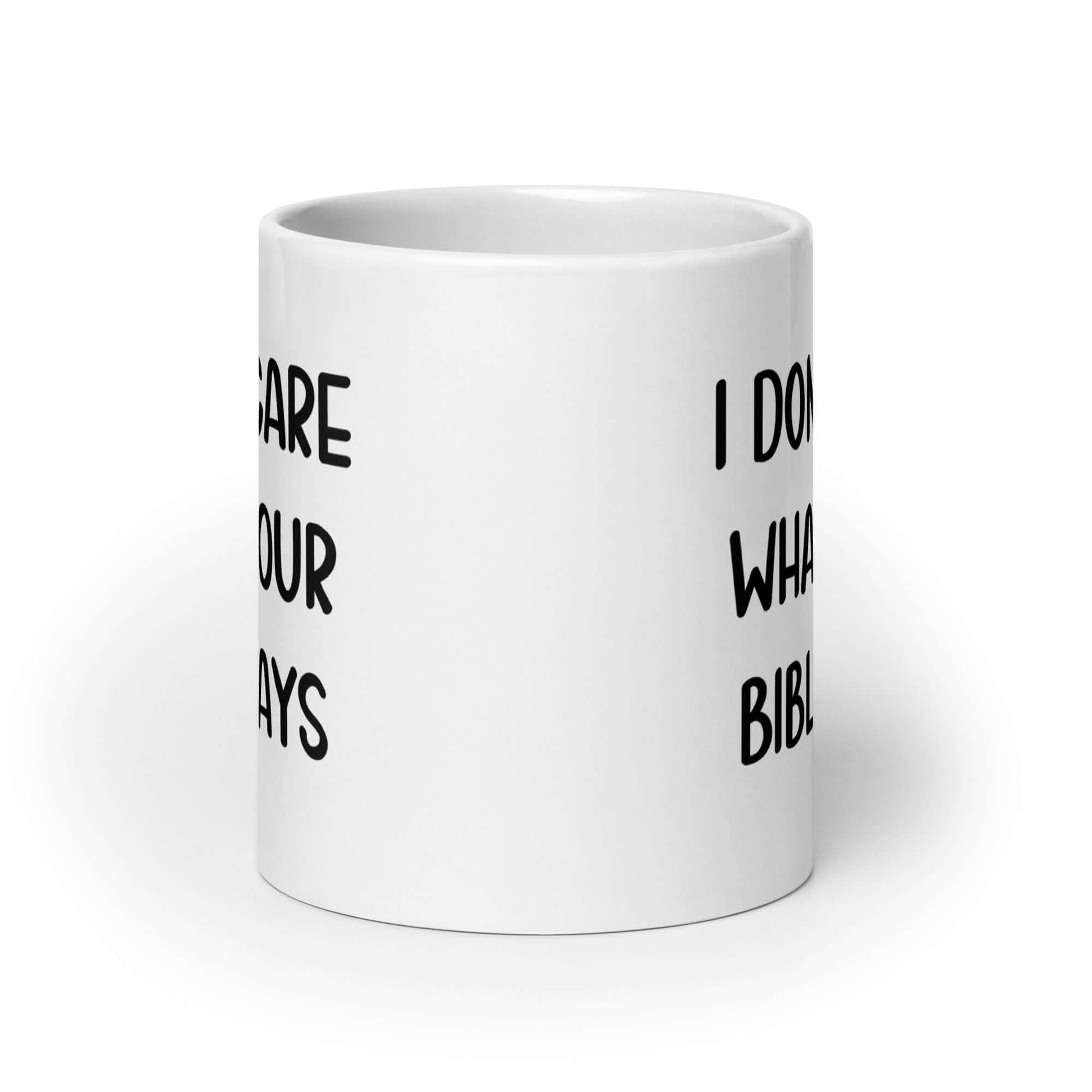 White ceramic mug with the words I don't care what your bible says printed on both sides.