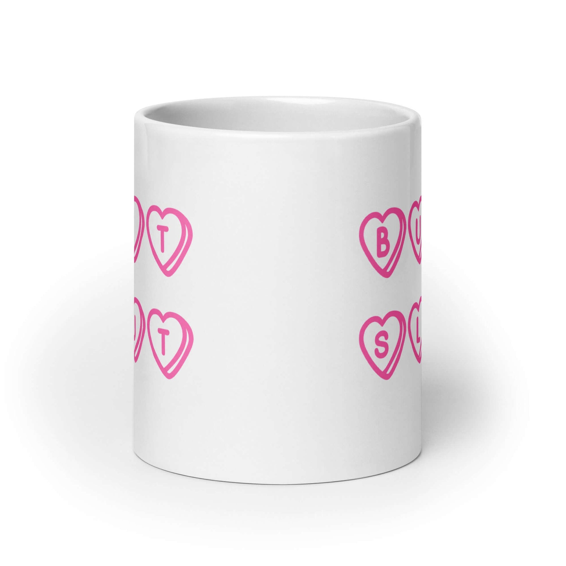 White ceramic mug with the words Butt Slut printed in pink on both sides. Pink hearts are around each letter in the text.