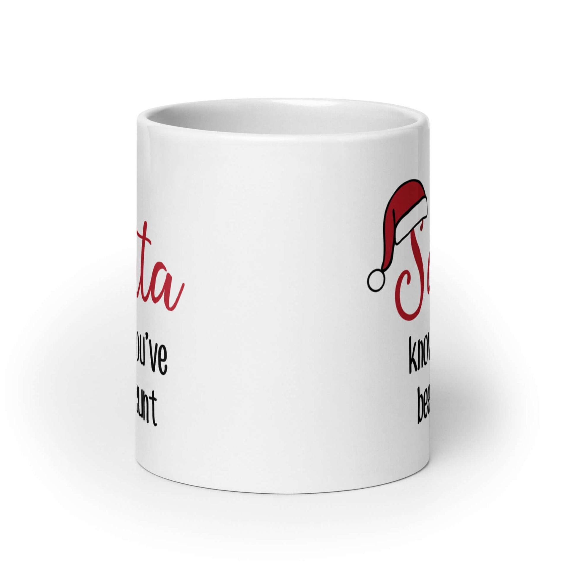 White ceramic mug with the words Santa knows you've been a cunt printed on both sides. There is a red Santa hat on the S in Santa.