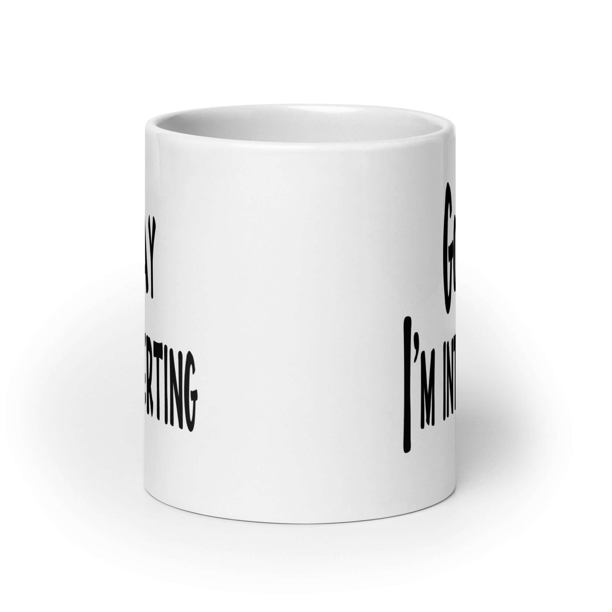 White ceramic coffee mug with the phrase Go away, I'm introverting printed on both sides of the mug.