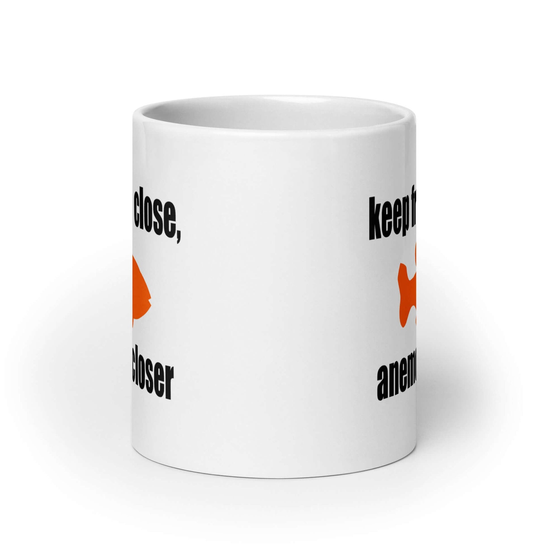 White ceramic coffee mug with the pun phrase Keep friends close, anemones closer with an image of an orange fish printed on both sides of the mug.