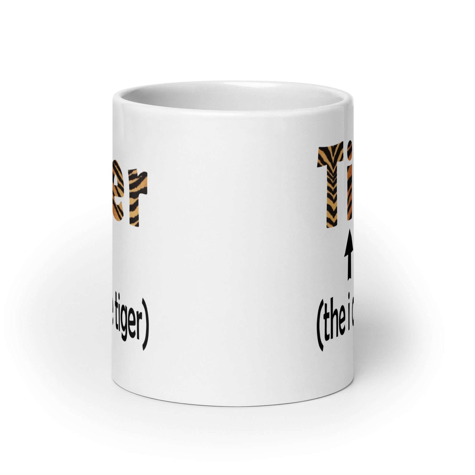 White ceramic coffee mug with the word Tiger printed in a tiger stripe font. In smaller letters beneath tiger it says the I of the tiger with an arrow pointing to the letting I in the words tiger. The graphics are printed on both sides of the mug.