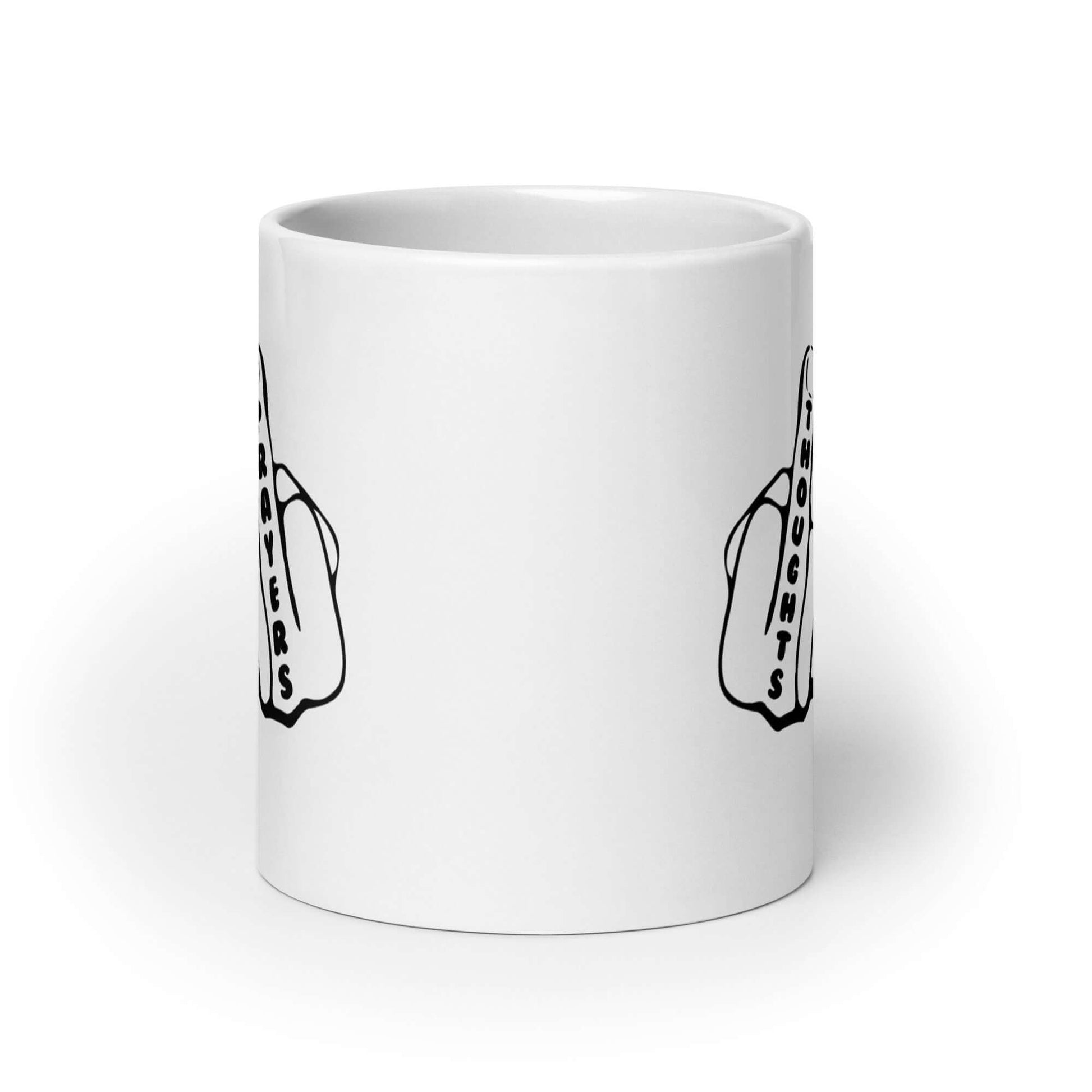 White ceramic coffee mug with an image of 2 line drawing hands with the middle fingers up. The word Thoughts is printed on one middle finger and the word Prayers is printed on the other middle finger. The graphics are printed on both sides of the mug.