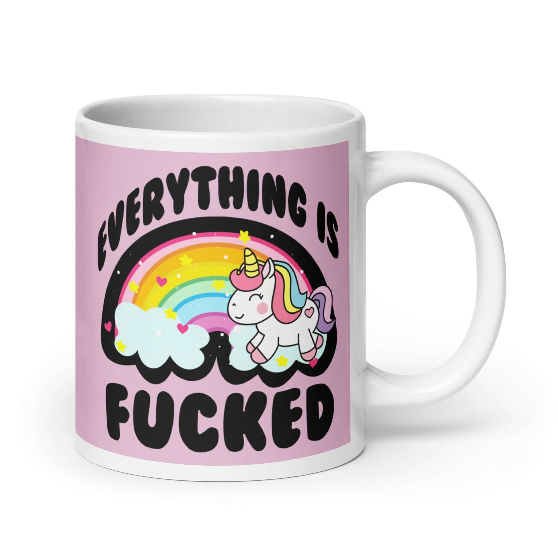 White ceramic coffee mug with a graphic of a kawaii style unicorn and a pastel rainbow with the words Everything is fucked printed on both sides. The background is pink.