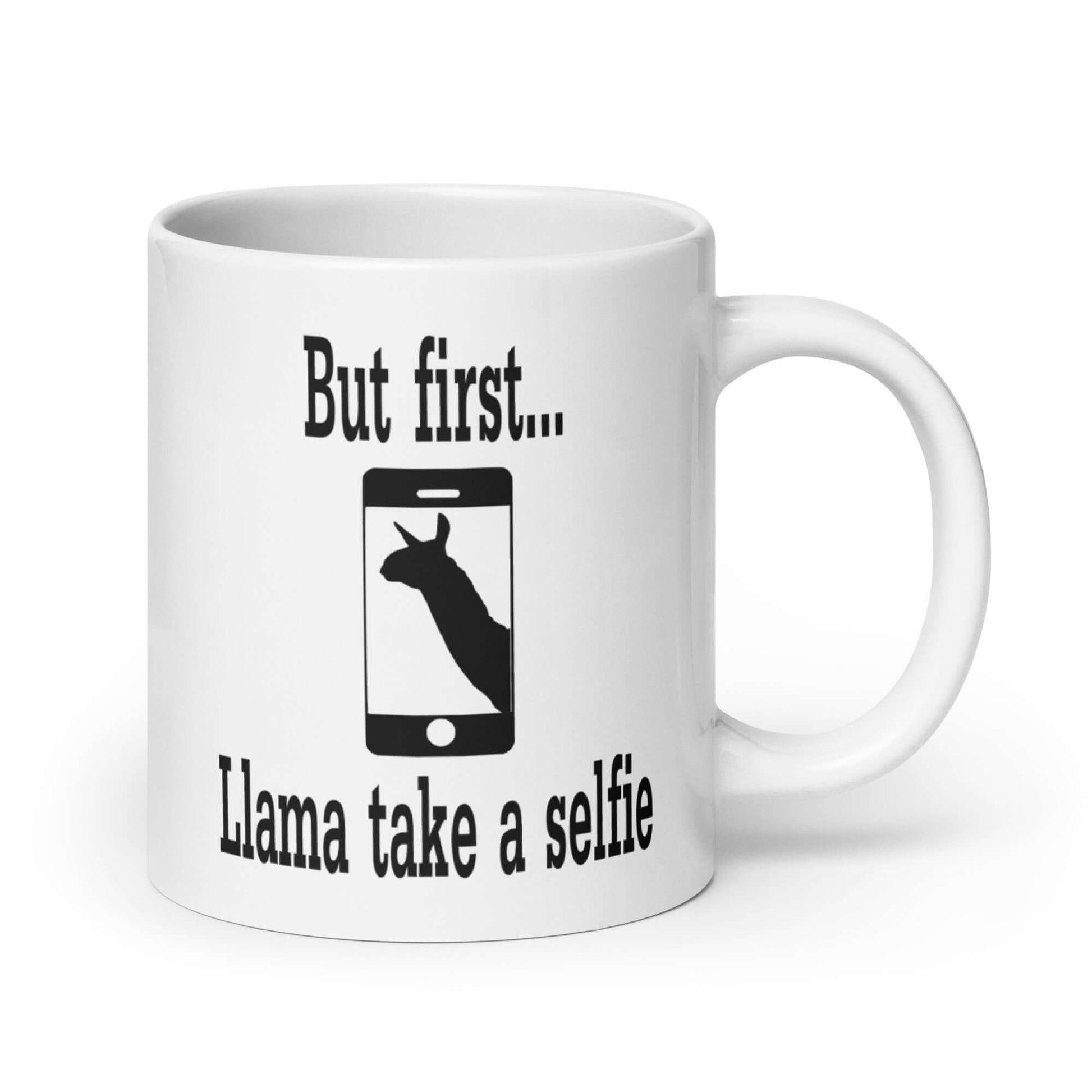 White ceramic coffee mug with image of an outline of a cell phone with image of a llama on the screen. The words But first...llama take a selfie are around the image. The graphic is printed on both sides of the mug,